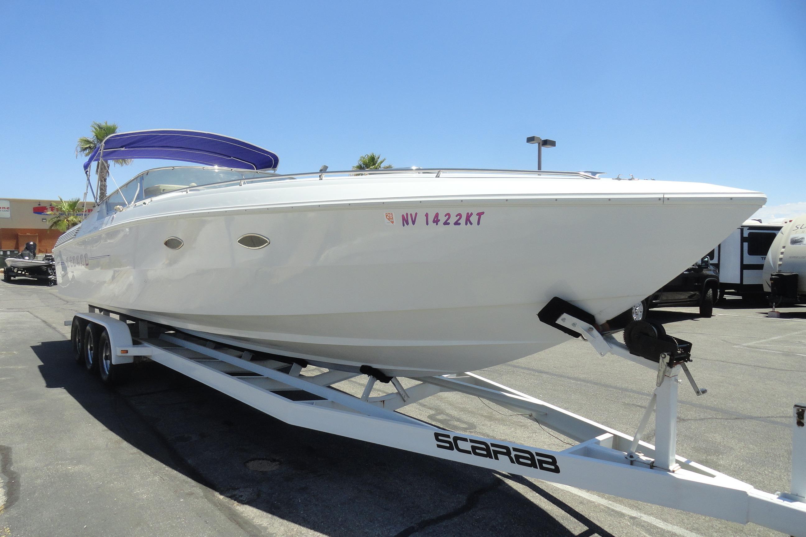 1988 Wellcraft 34 Scarab boat on trailer, parked outdoors under clear blue sky.