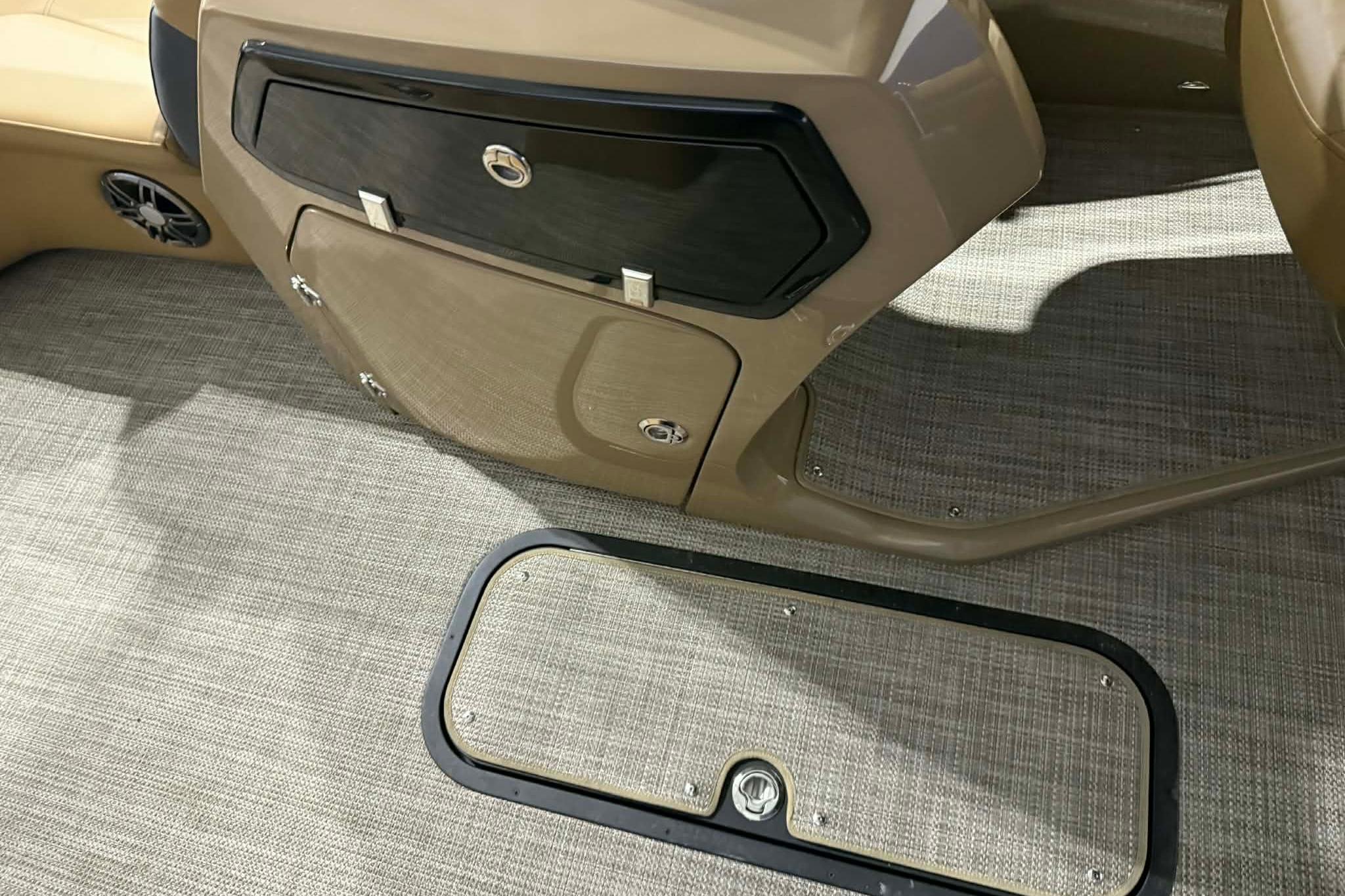 Interior of 2026 Manitou Encore VP 230 boat, featuring storage compartments and carpeted flooring.