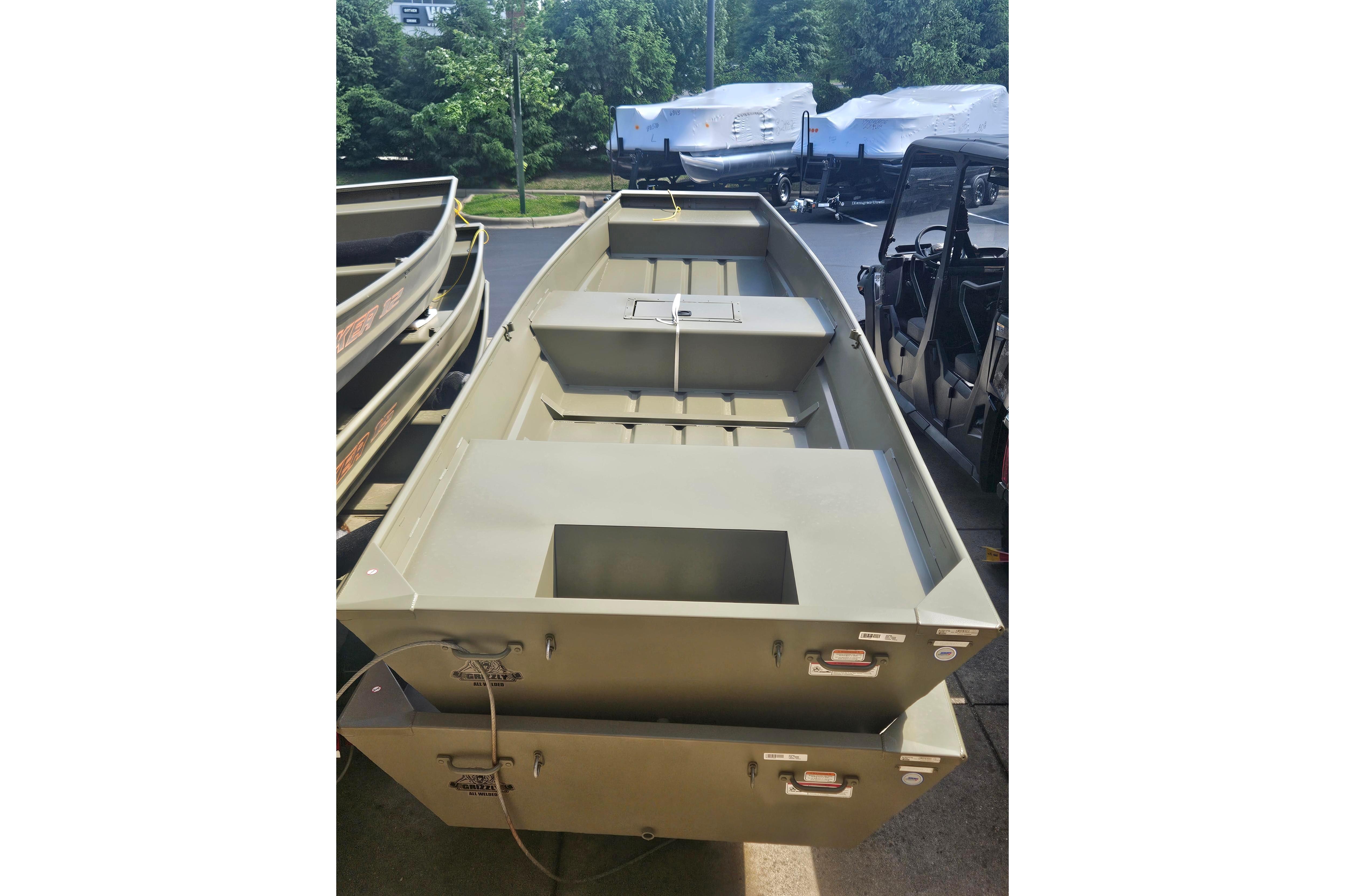 2026 Tracker Grizzly 15 Jon boat displayed outdoors, surrounded by greenery.
