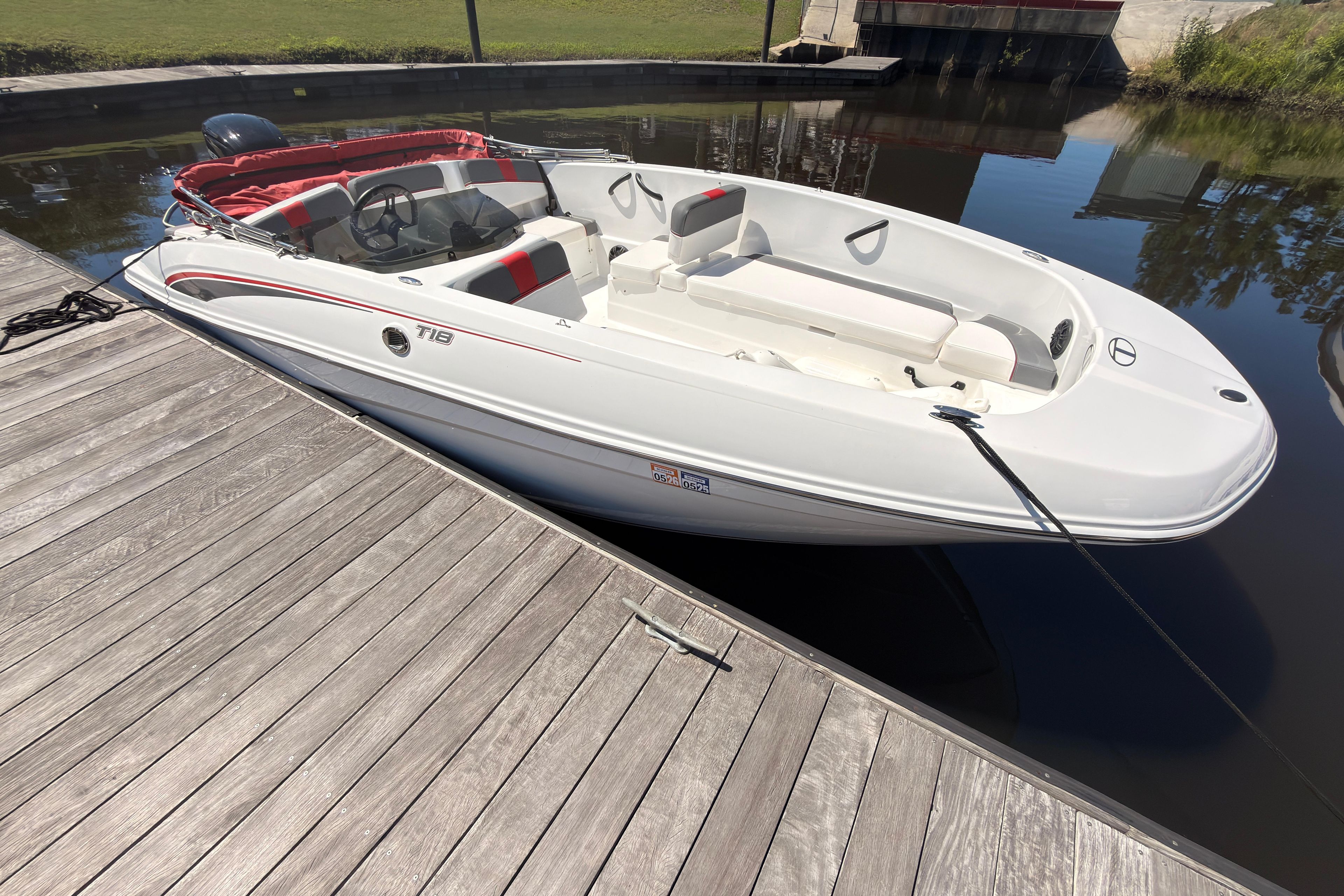 2022 Tahoe T18 boat docked on calm water, featuring sleek white design and red accents.