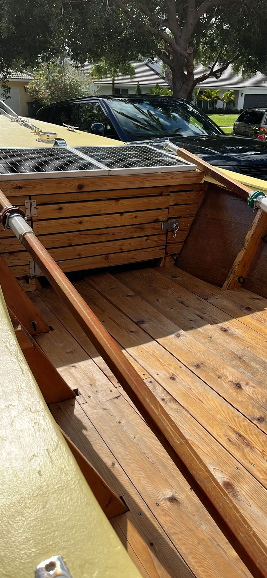 A wooden dory boat with oar, parked in a residential area.