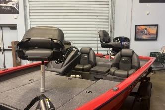 2026 Tracker Pro Team 175 boat with red exterior and black seats in a garage.
