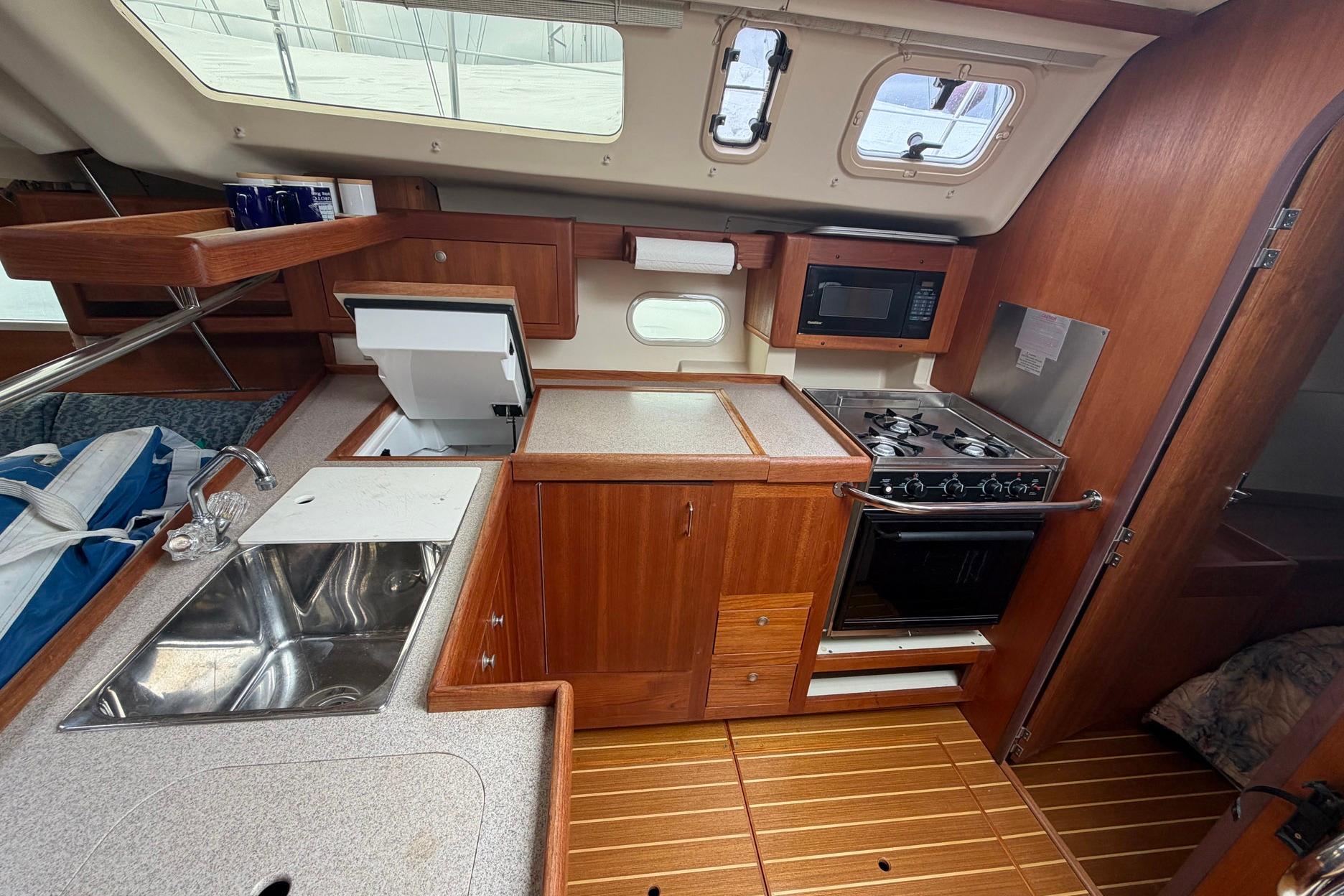 Interior of a 1998 Hunter 410 sailboat kitchen with stove, sink, and microwave.