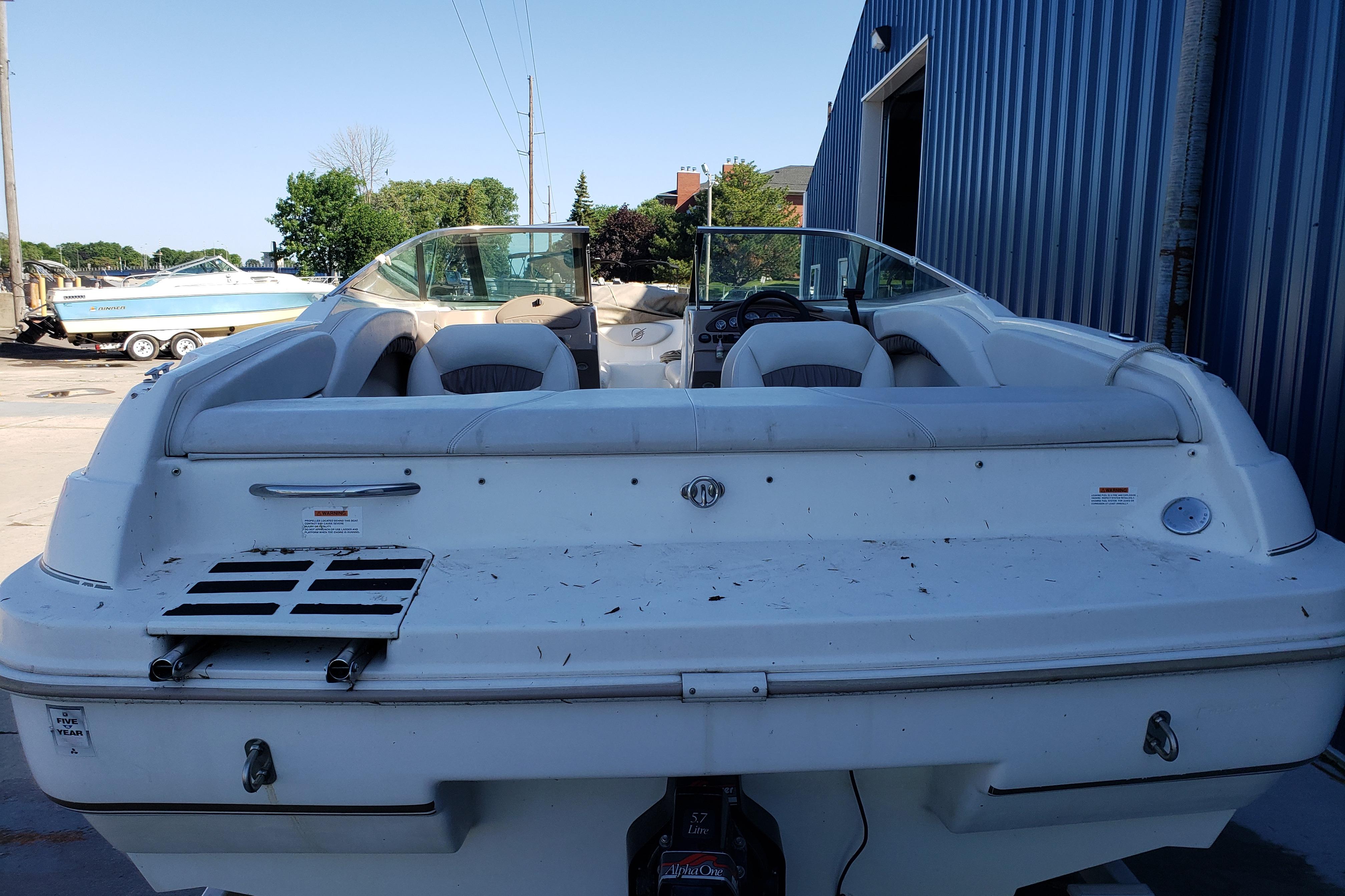 1998 Wellcraft Eclipse 2000 SS boat, rear view, parked near blue building.