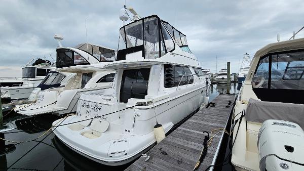 2000 Carver 450 Voyager Pilothouse yacht docked at marina under cloudy sky.
