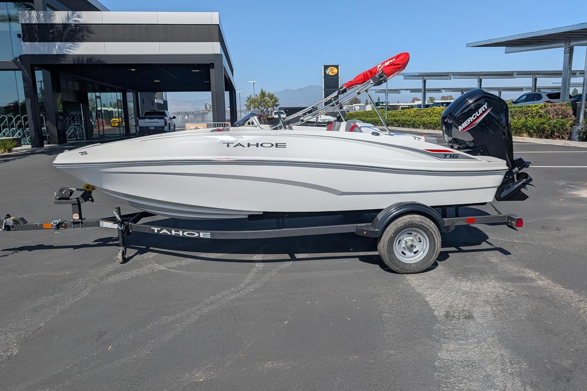 2026 Tahoe T16 boat on trailer, parked outside a modern building.