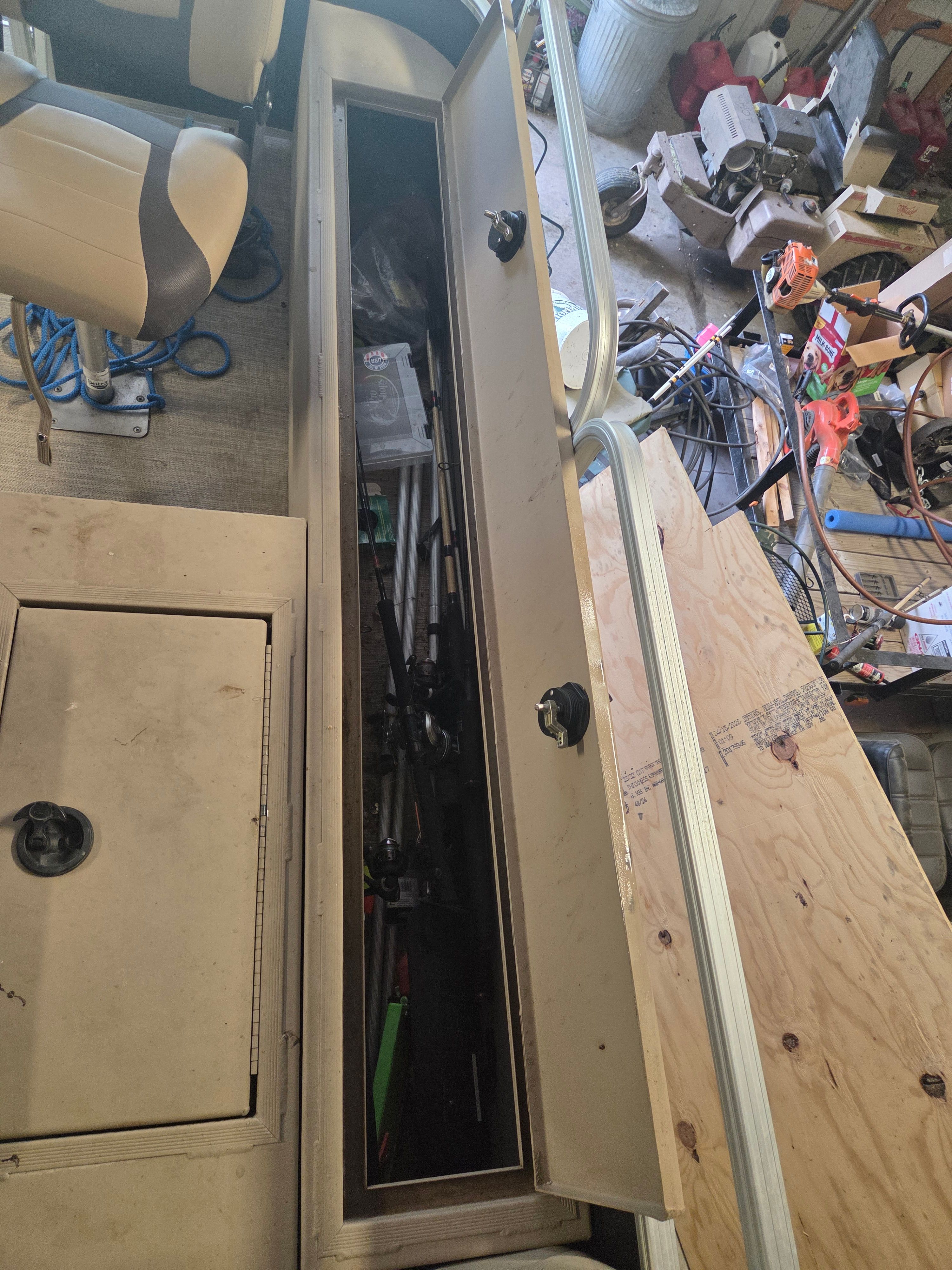 Interior view of a boat with storage compartment and fishing rods.