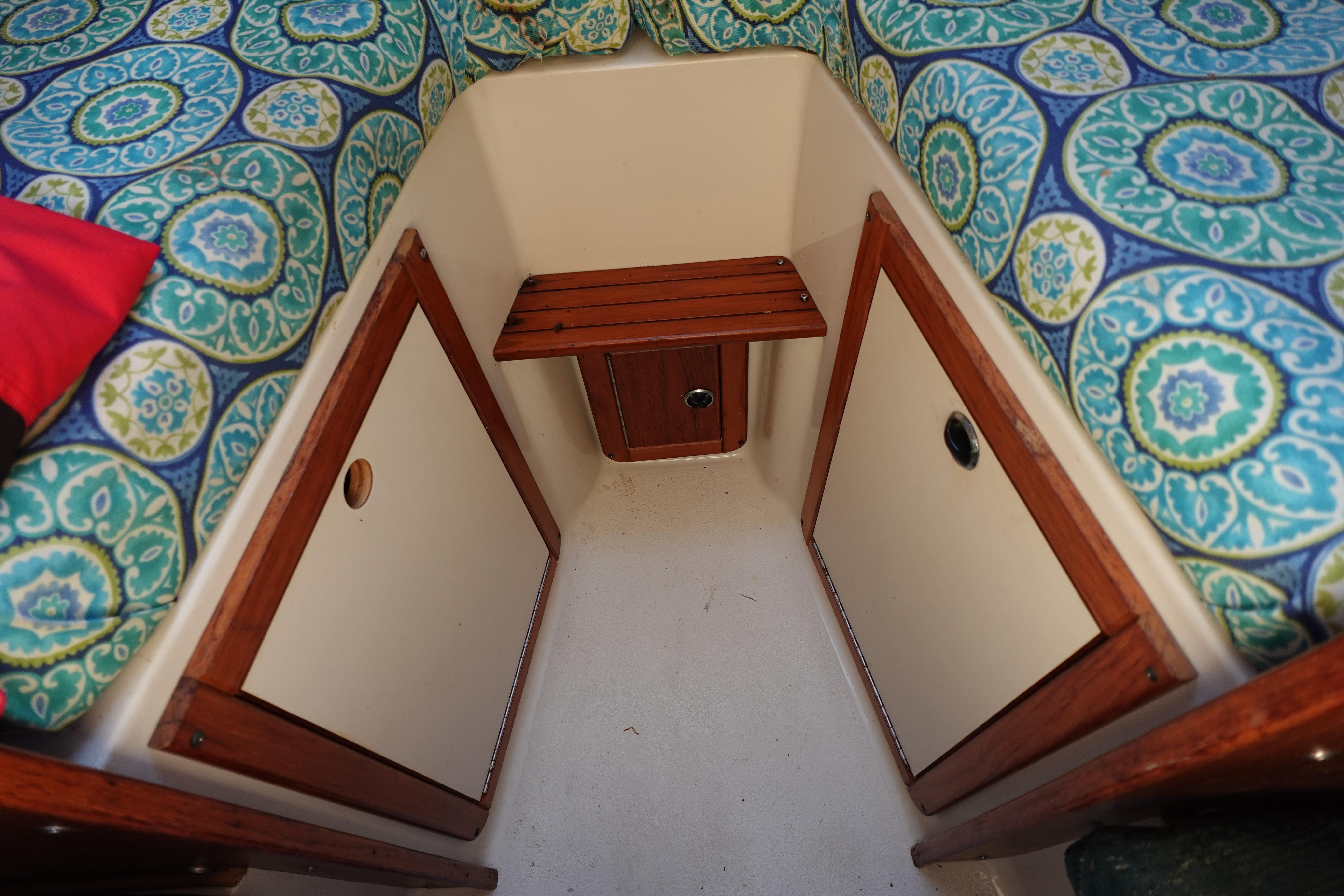 Interior of a 1997 Catalina 28 sailboat with patterned cushions and wooden storage.
