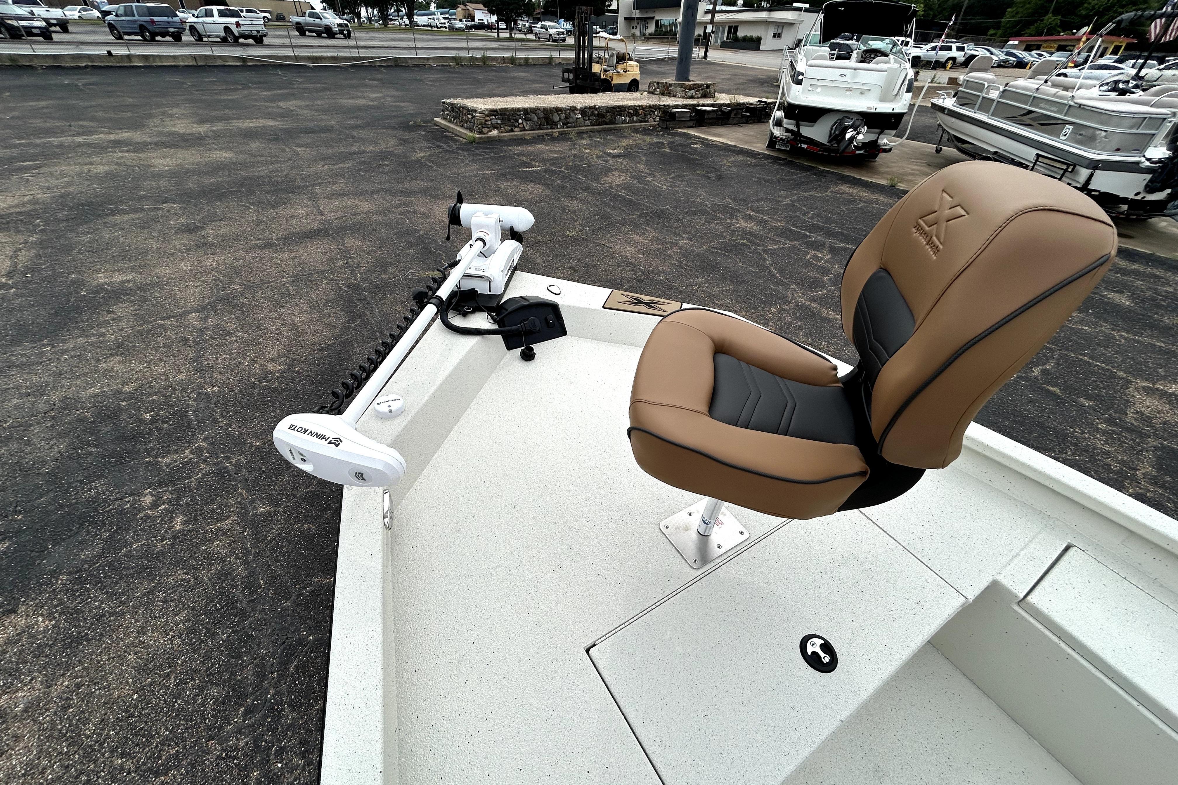 2026 Xpress H20B Bay boat with tan seat and trolling motor in a parking lot.