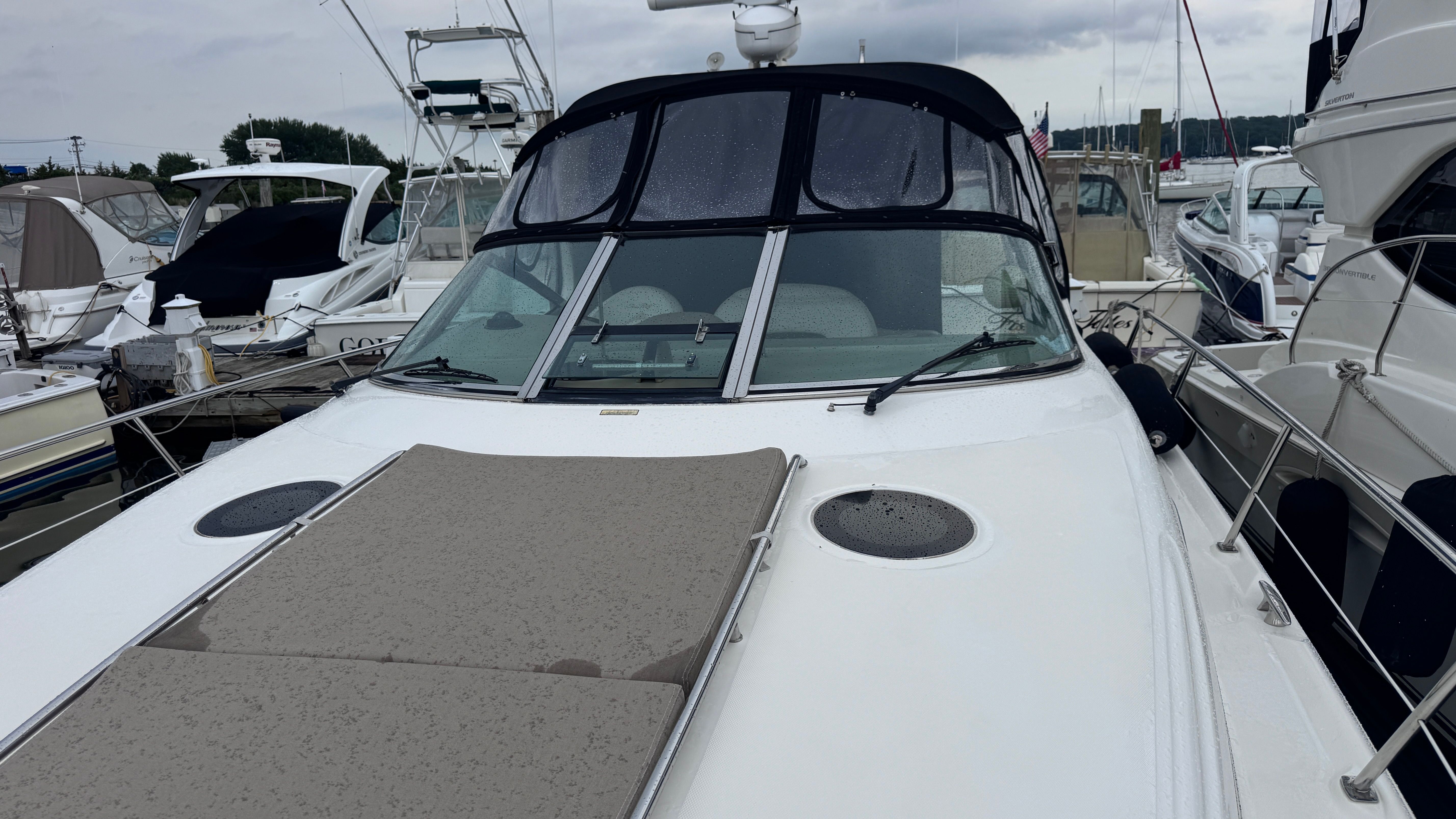 A 2003 Sea Ray 360 Sundancer docked at a marina. It features a large foredeck with sun pads.