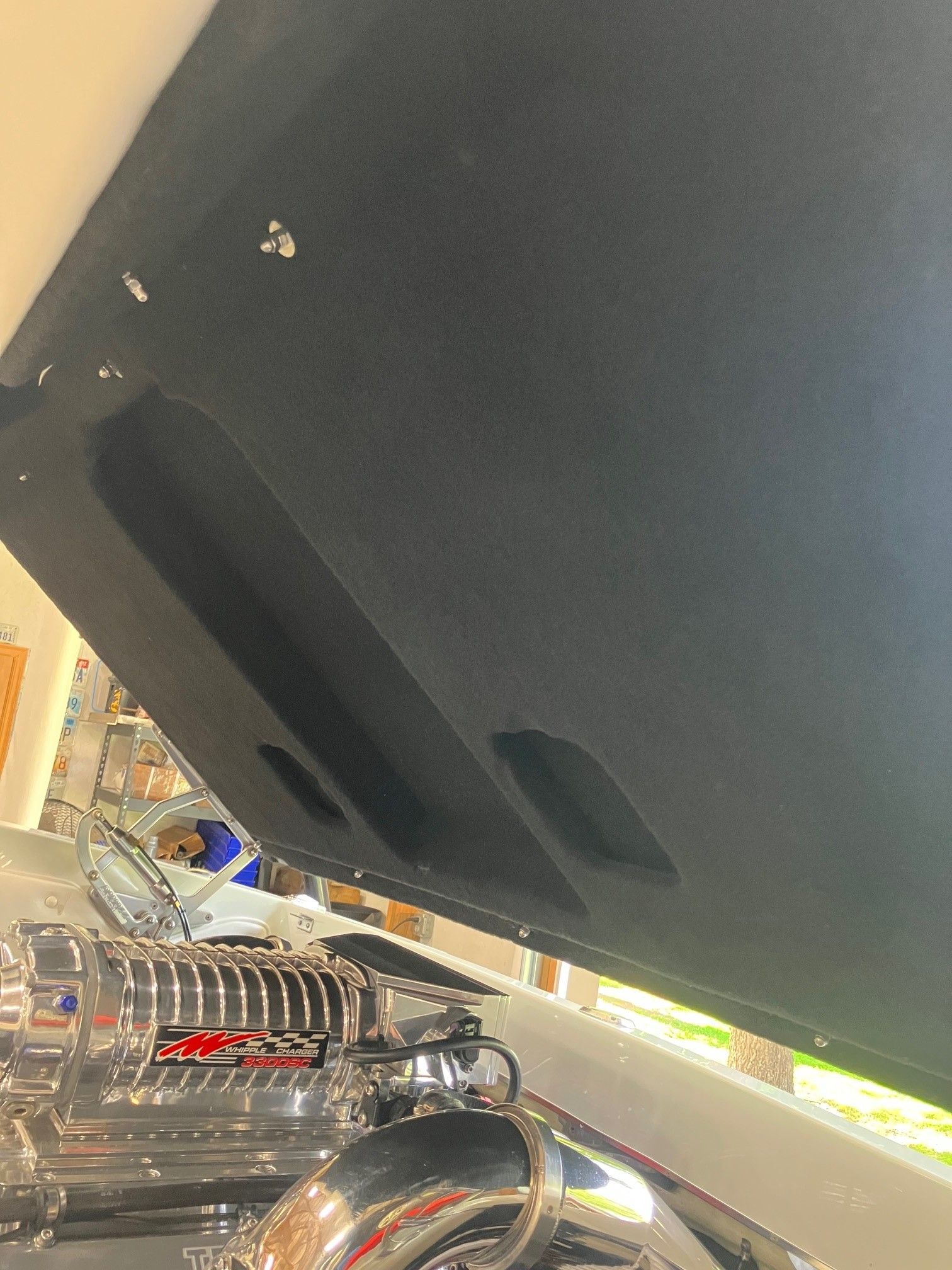 Close-up of an engine compartment with a shiny engine and black cover.