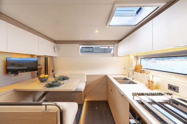 Modern interior of 2025 Lagoon 60 yacht with kitchen and dining area.