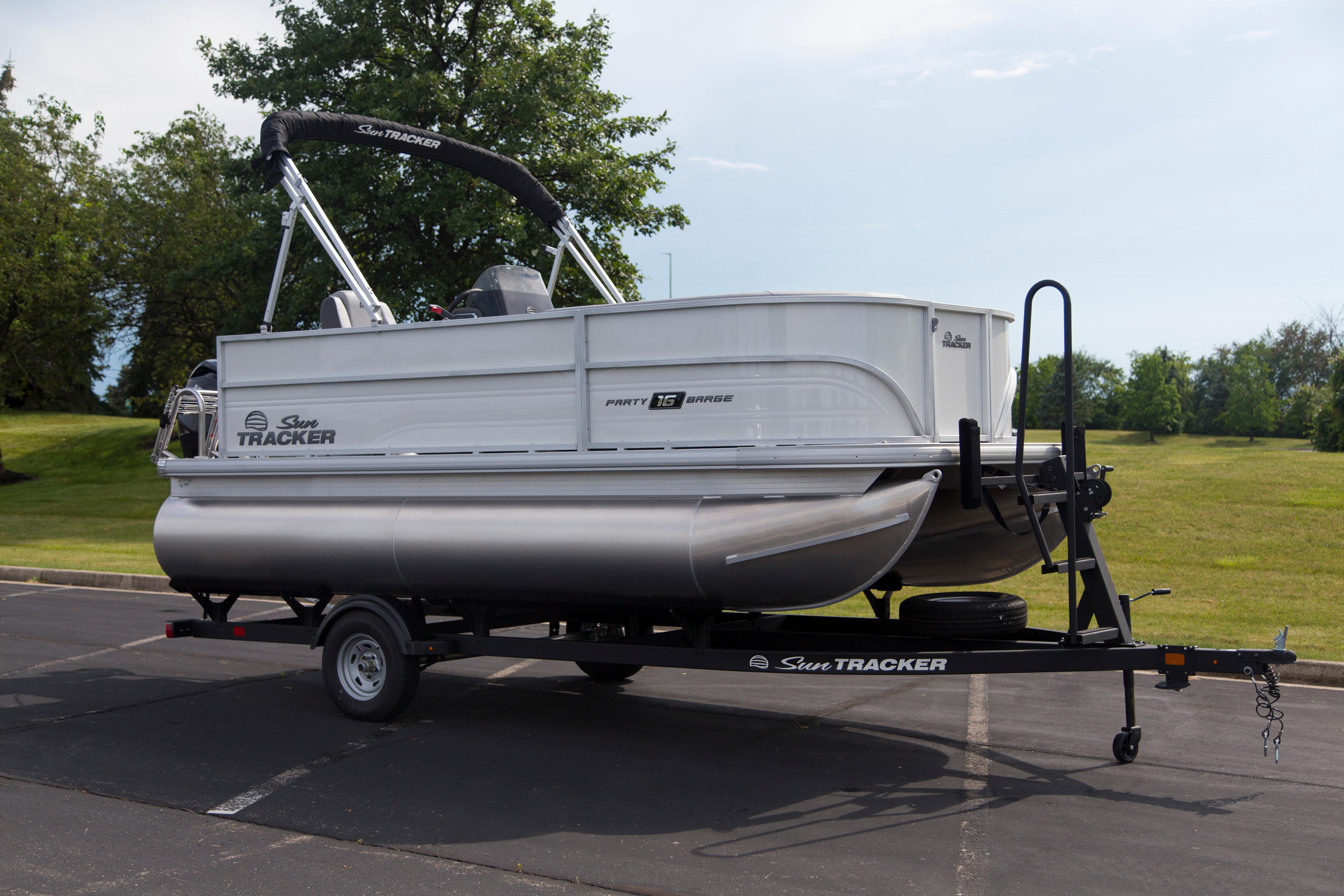 2026 Sun Tracker Party Barge 16 DLX pontoon boat on trailer in a parking lot.