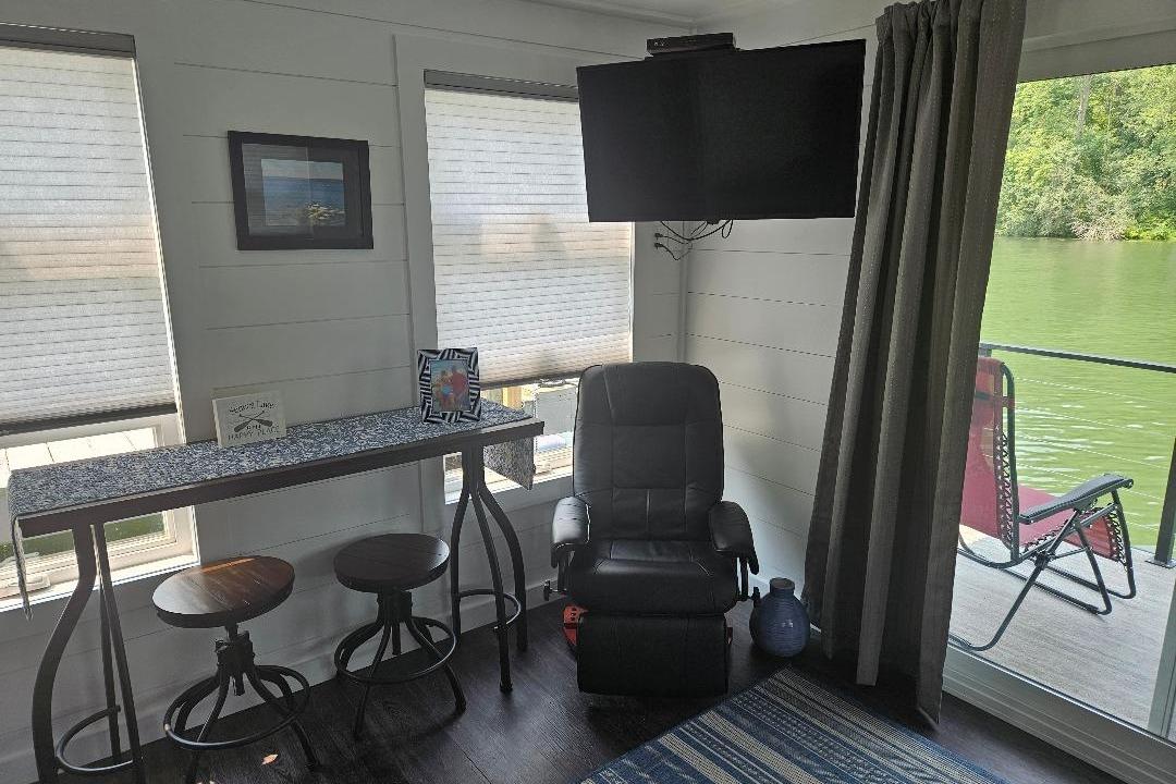 Interior of 2021 East Coast Houseboats Freedom 40 with seating, TV, and lake view.