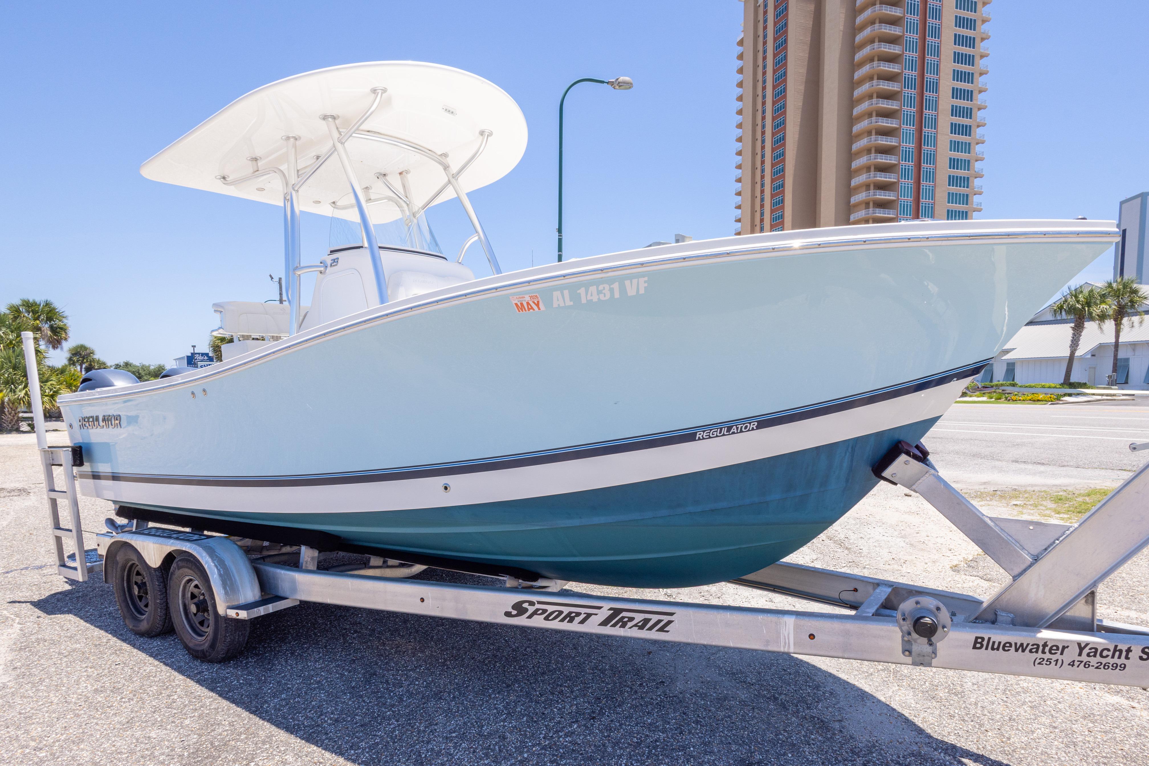 2019 Regulator 23 Center Console boat on trailer, parked near a tall building.
