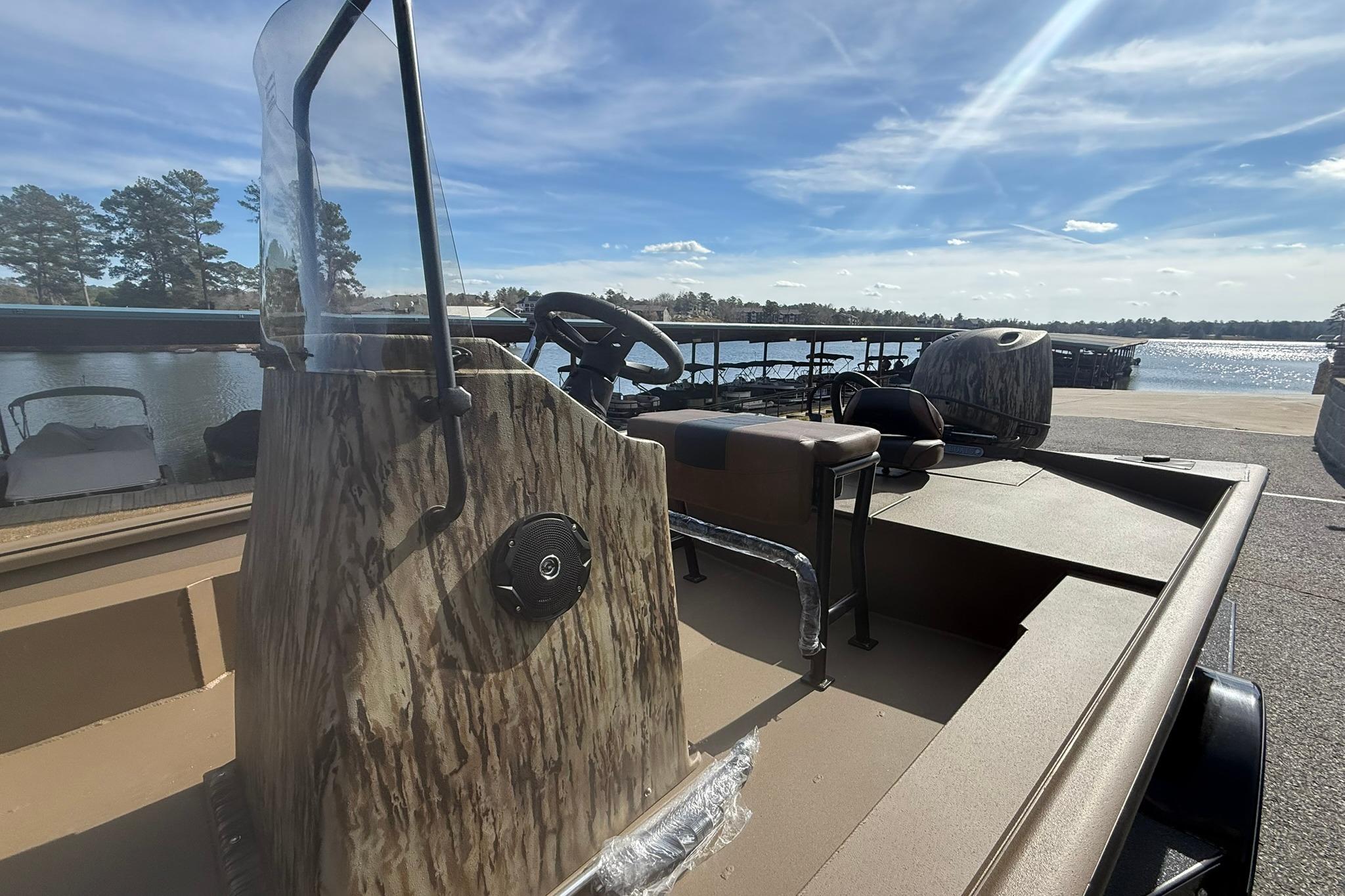 2026 Excel 206 Stalker CC boat with camouflage design, docked by a scenic lake.