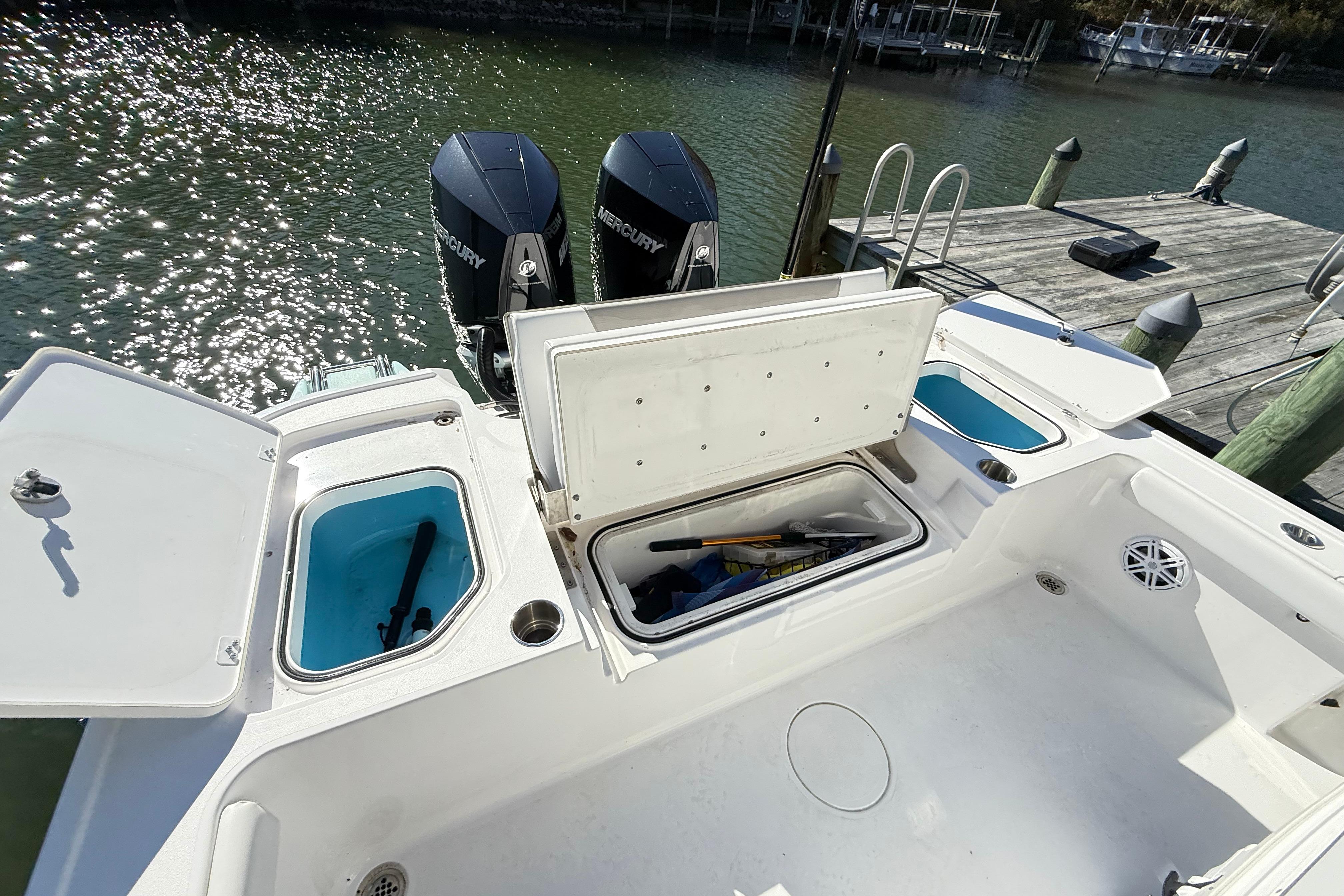 2023 Caymas 281 HB boat with open storage compartments and dual Mercury engines.