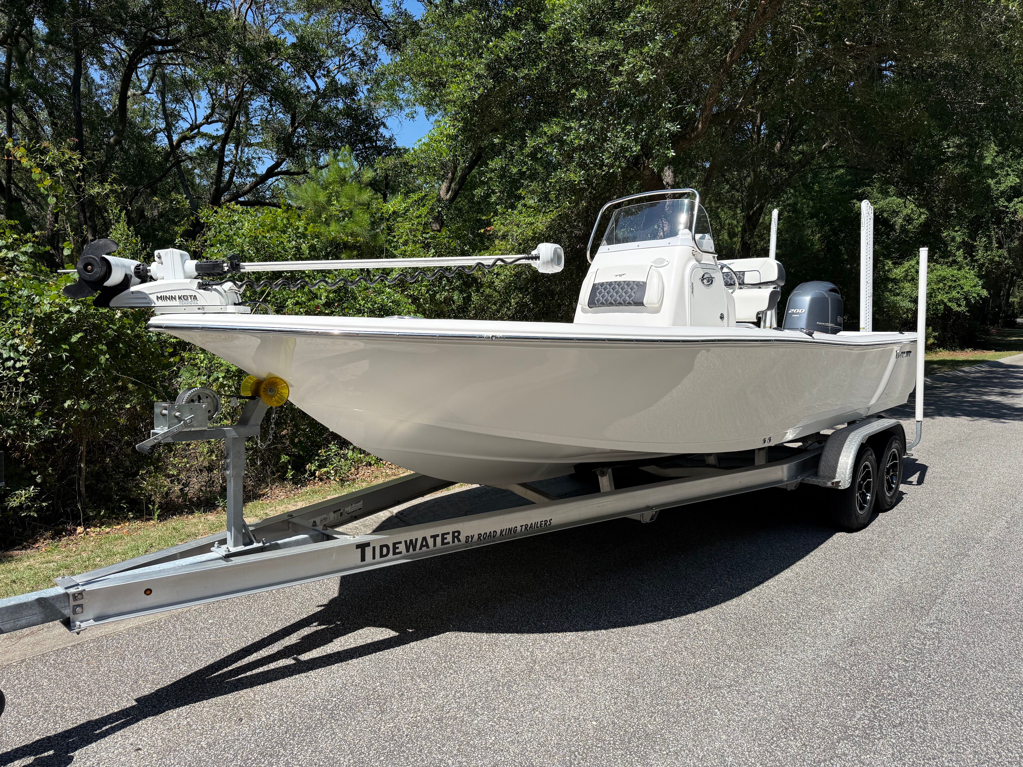 A 2023 Tidewater 2210 Carolina Bay boat on a trailer, surrounded by trees.