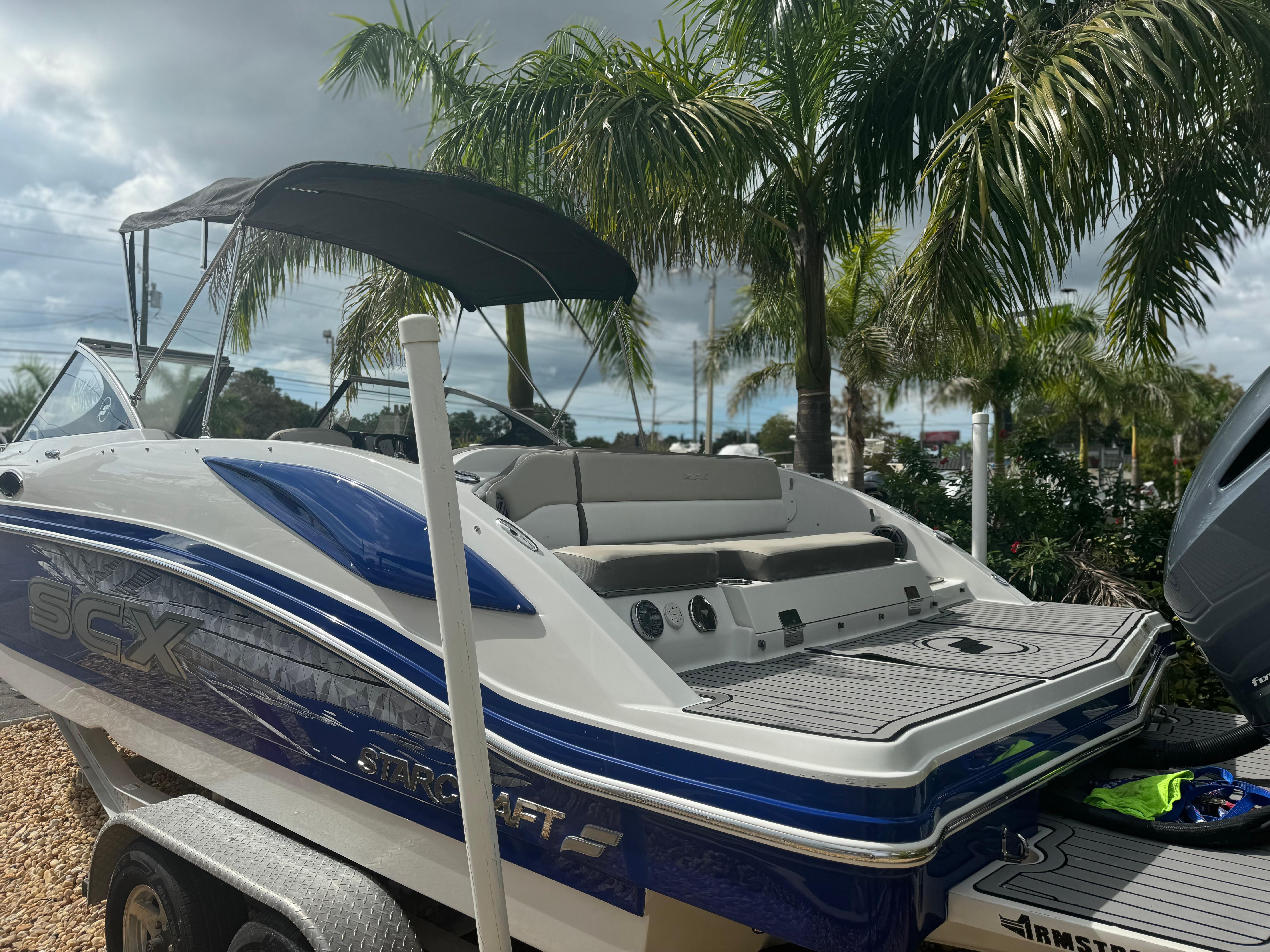 2017 Starcraft 230 OB SCX EXT boat with canopy, parked near palm trees.
