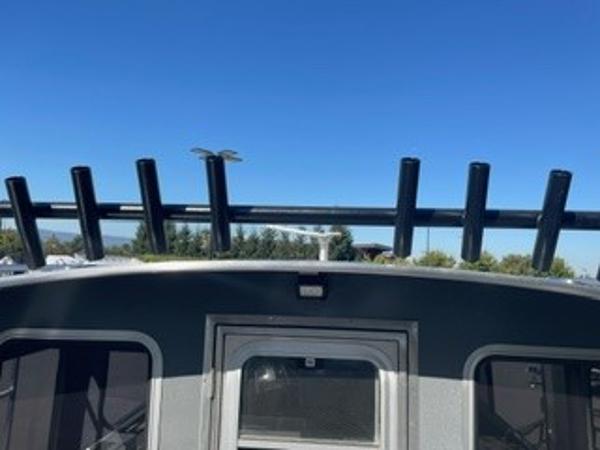2025 Spartan 2600 Olympia boat with rod holders against a clear blue sky.