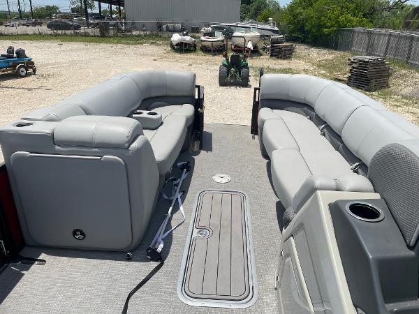 2023 Regency 250 DL3 pontoon boat with spacious gray seating in a yard setting.