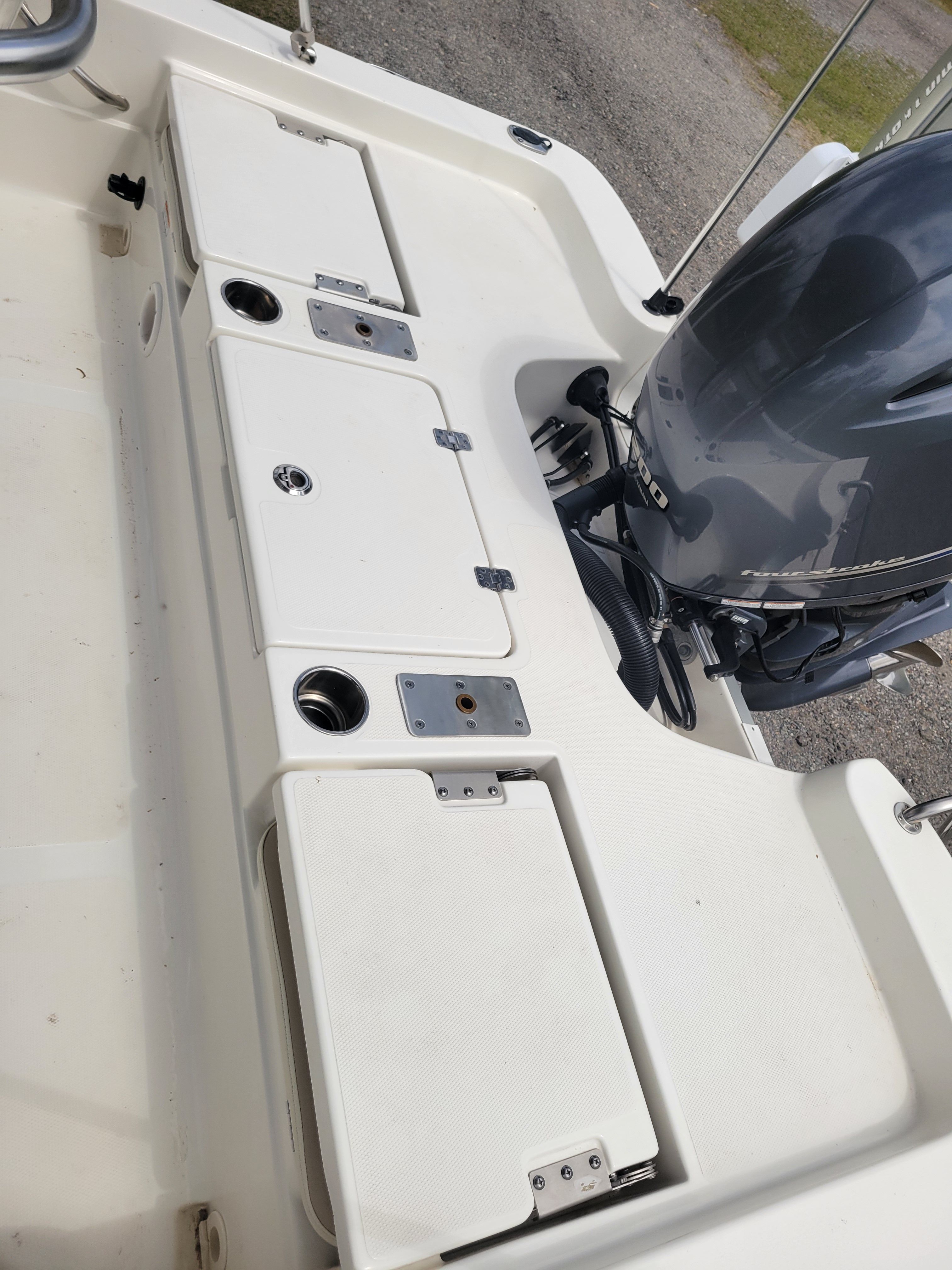 A white boat with an outboard motor and several storage compartments.