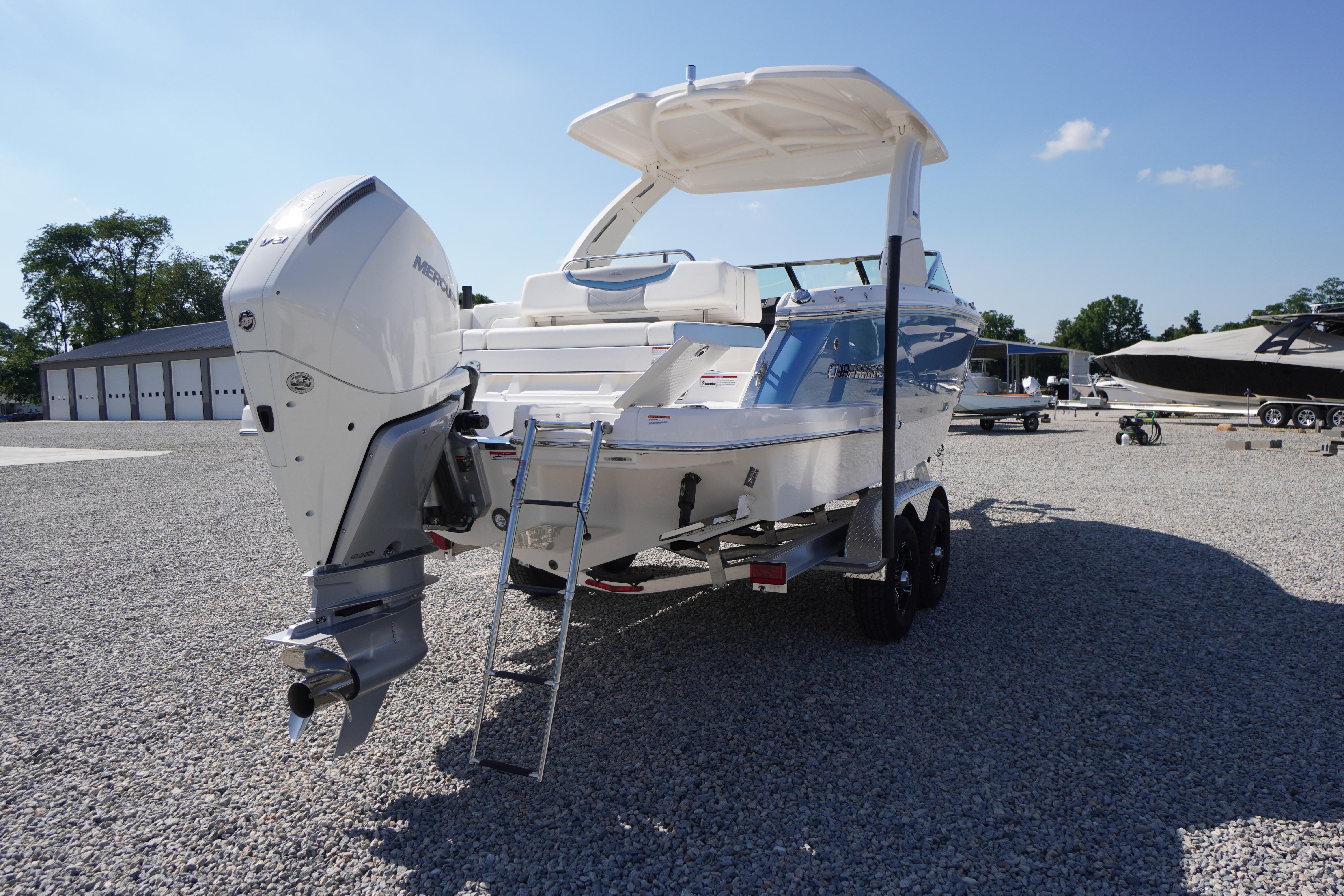 2026 Chaparral 270 OSX boat with outboard motor on a gravel lot under clear sky.