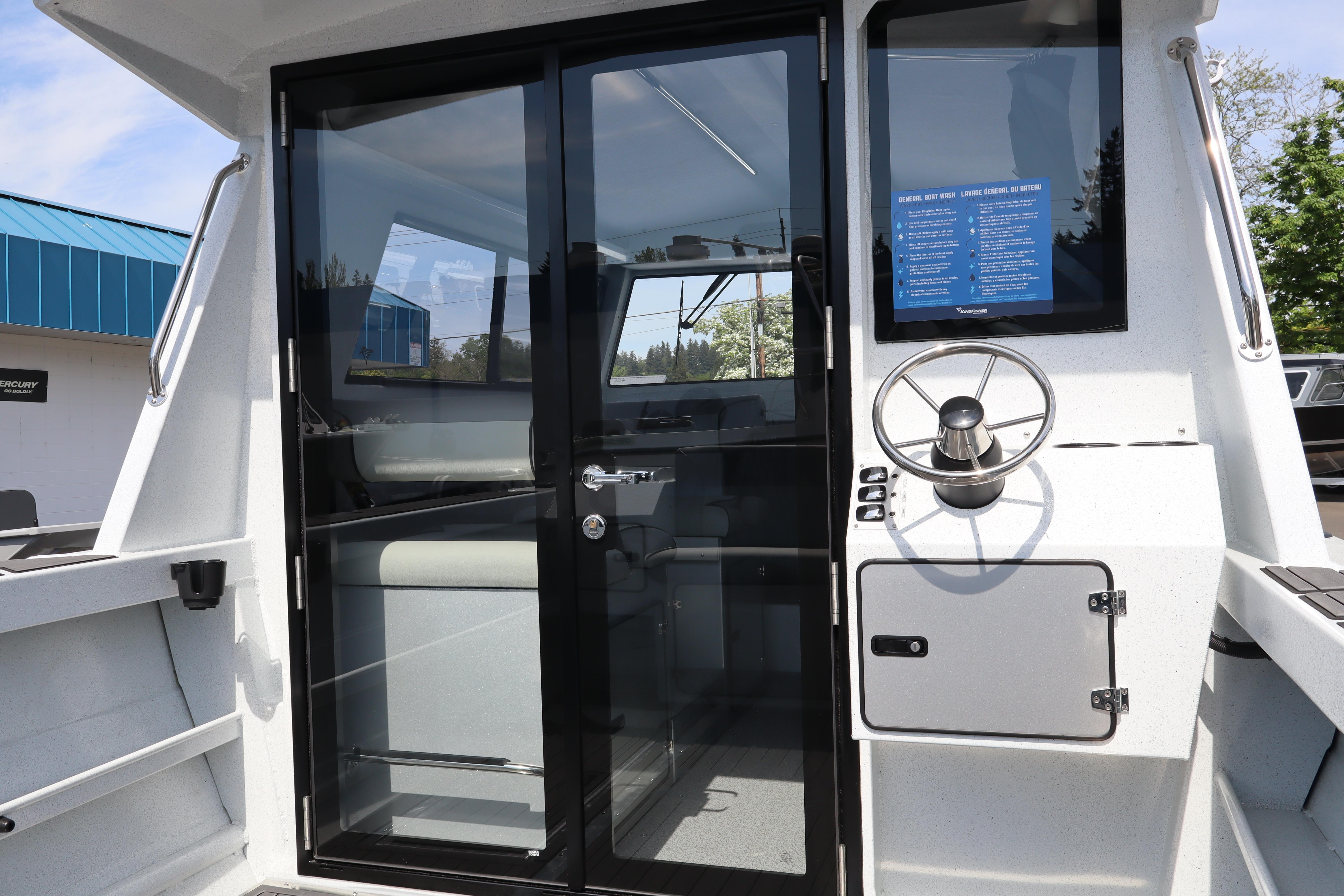 2026 KingFisher 25 XAC boat interior with steering wheel and glass door.