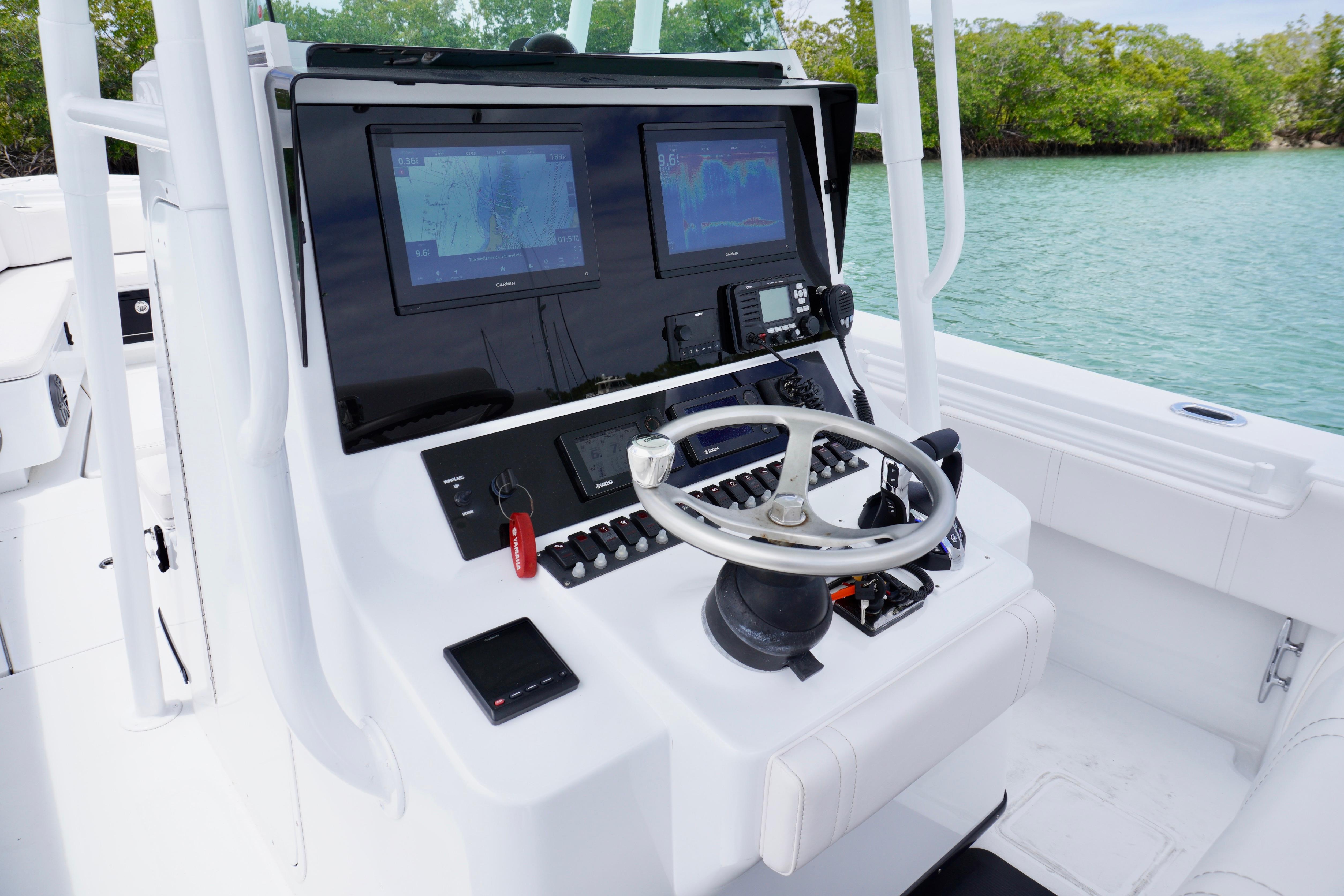 Center console of a 2013 Contender 35 LS boat with navigation screens and steering wheel.