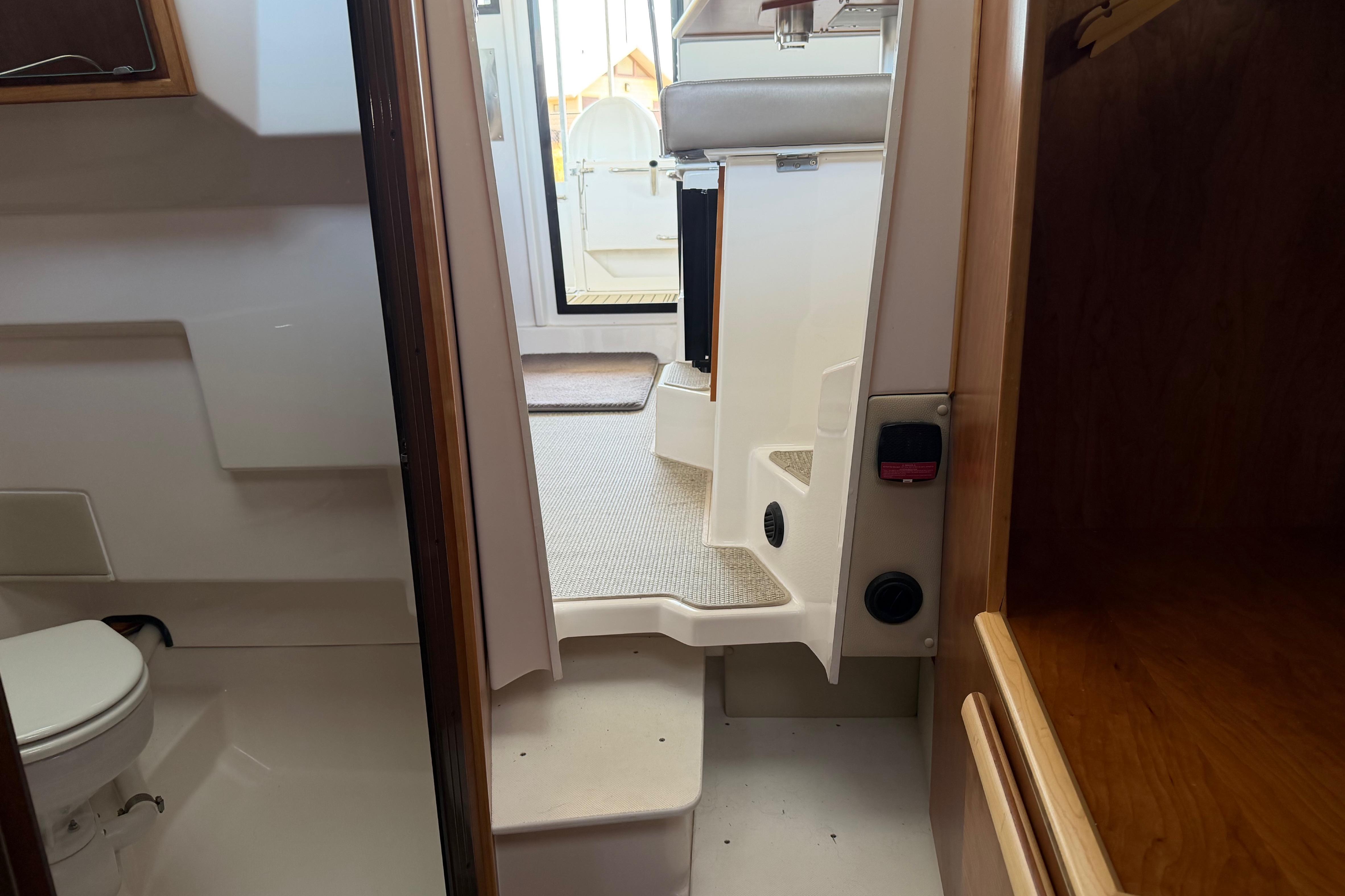 Interior view of 2023 Cutwater C-288 Coupe, featuring cabin steps and compact bathroom.
