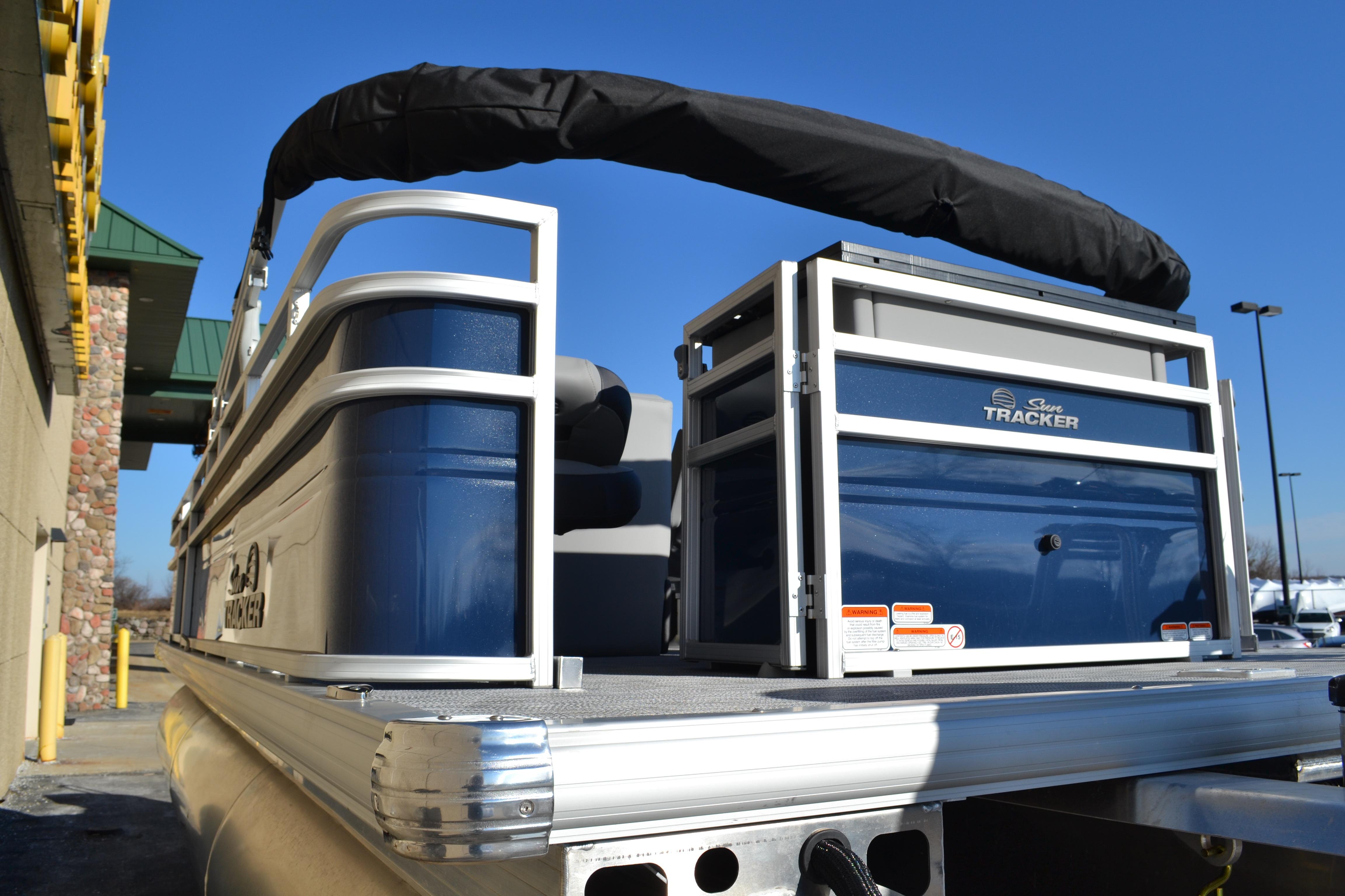 2026 Sun Tracker SportFish 22 XP3 pontoon boat, blue and silver, docked outdoors.