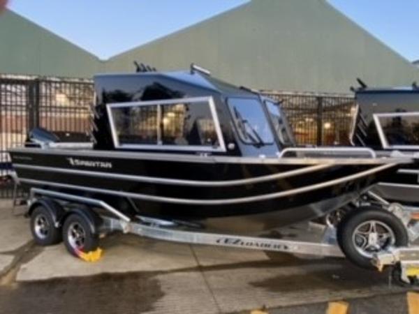 2024 Spartan 200 Astoria boat on trailer, sleek black design, parked outdoors.