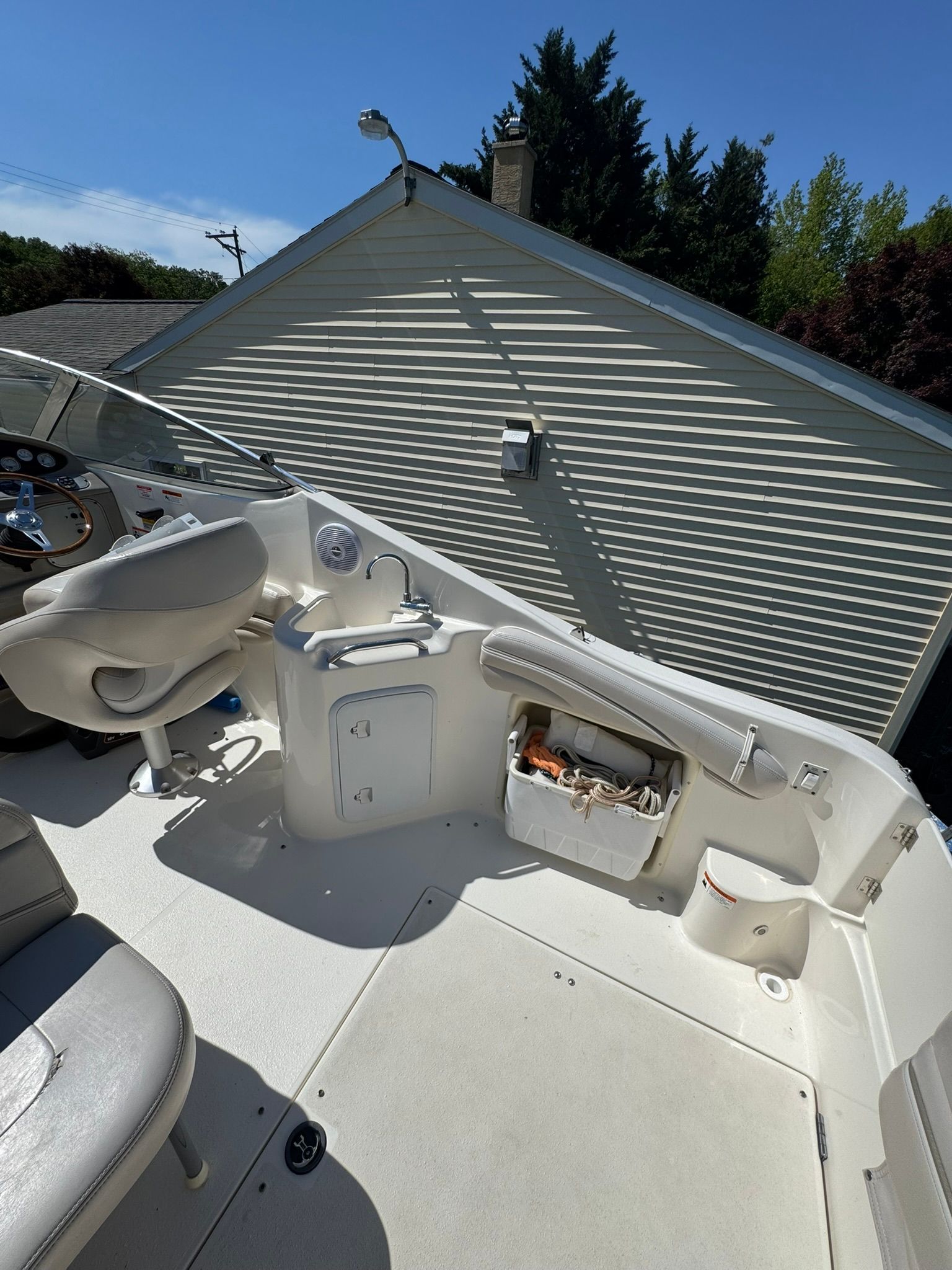The boat features a clean, white deck with a seat and a sink.