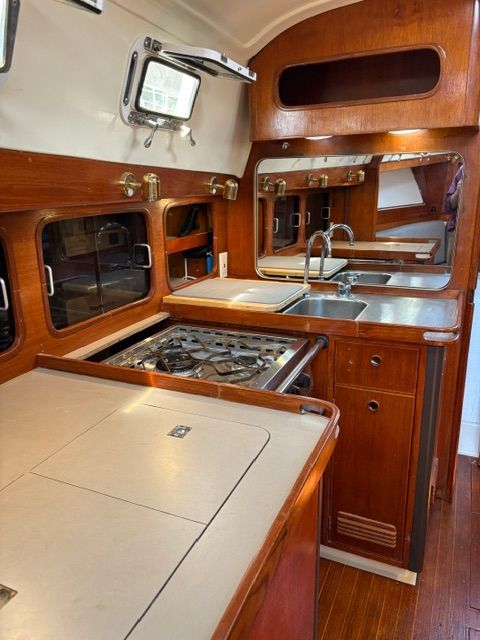 Interior of a 1983 C&C Landfall with wooden cabinetry and stainless steel sink.