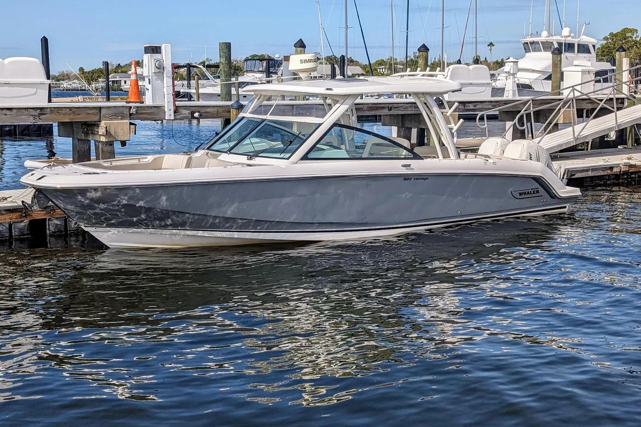 2017 Boston Whaler 320 Vantage boat docked at a marina, reflecting on calm water.