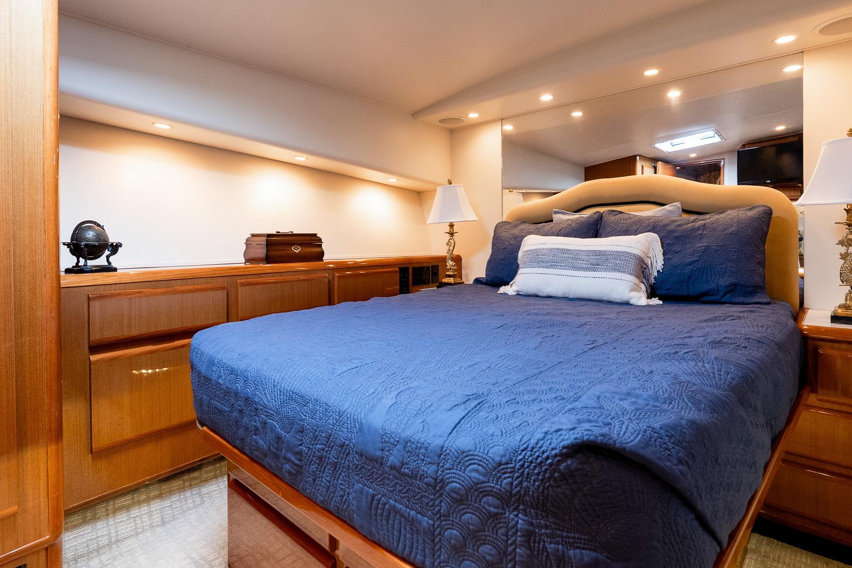 Luxurious bedroom interior of a 2000 Viking 50' Convertible yacht with elegant wood finishes.