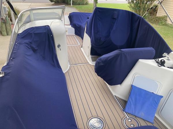2006 Hurricane SunDeck 237 OB boat interior with blue covers and wooden deck.