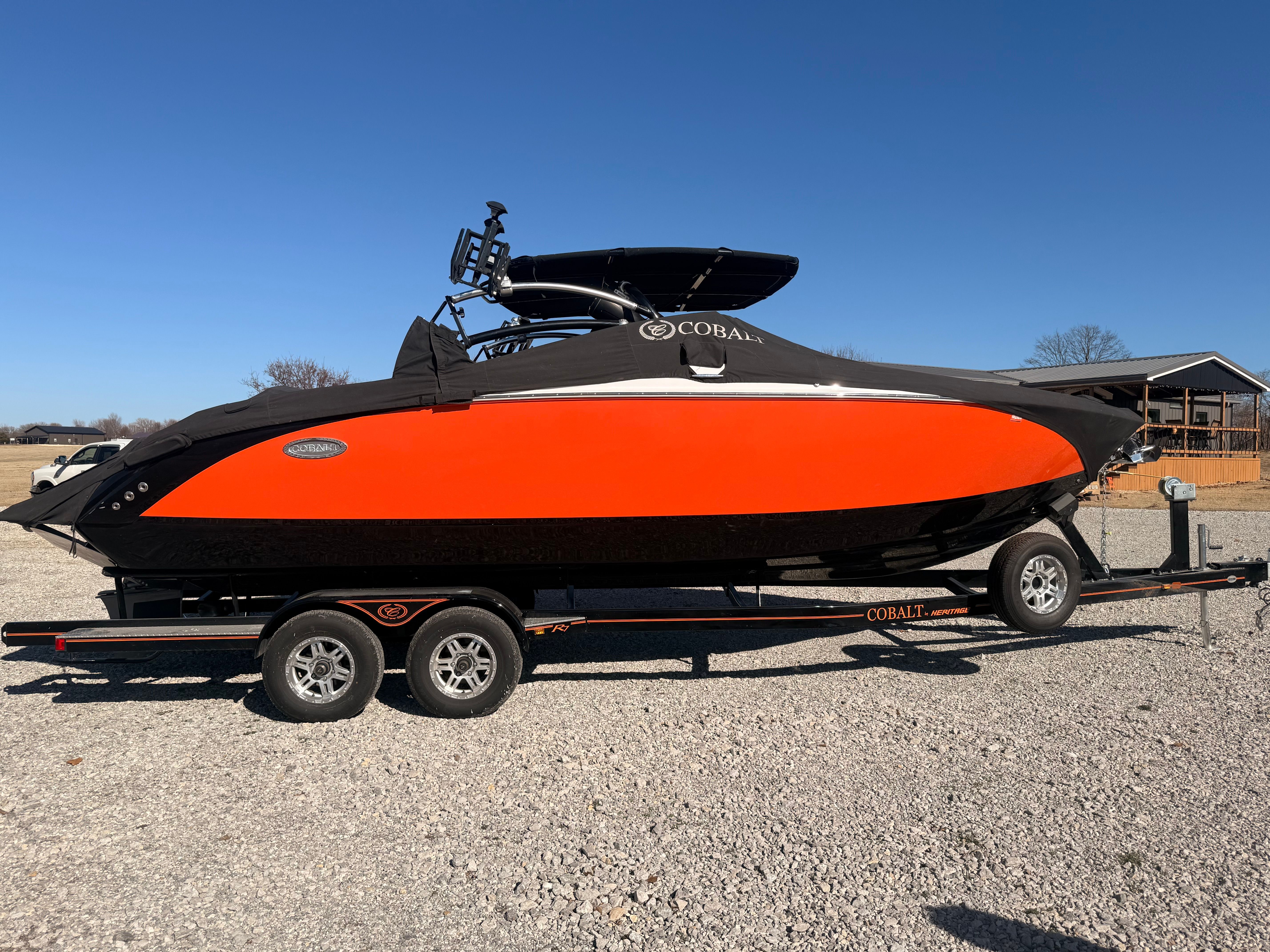 A 2019 Cobalt R7 Surf boat on a trailer, featuring a striking orange and black design.