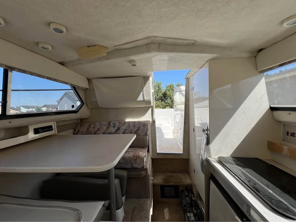 Interior of a 1999 Bayliner 2452 with table and seating area.