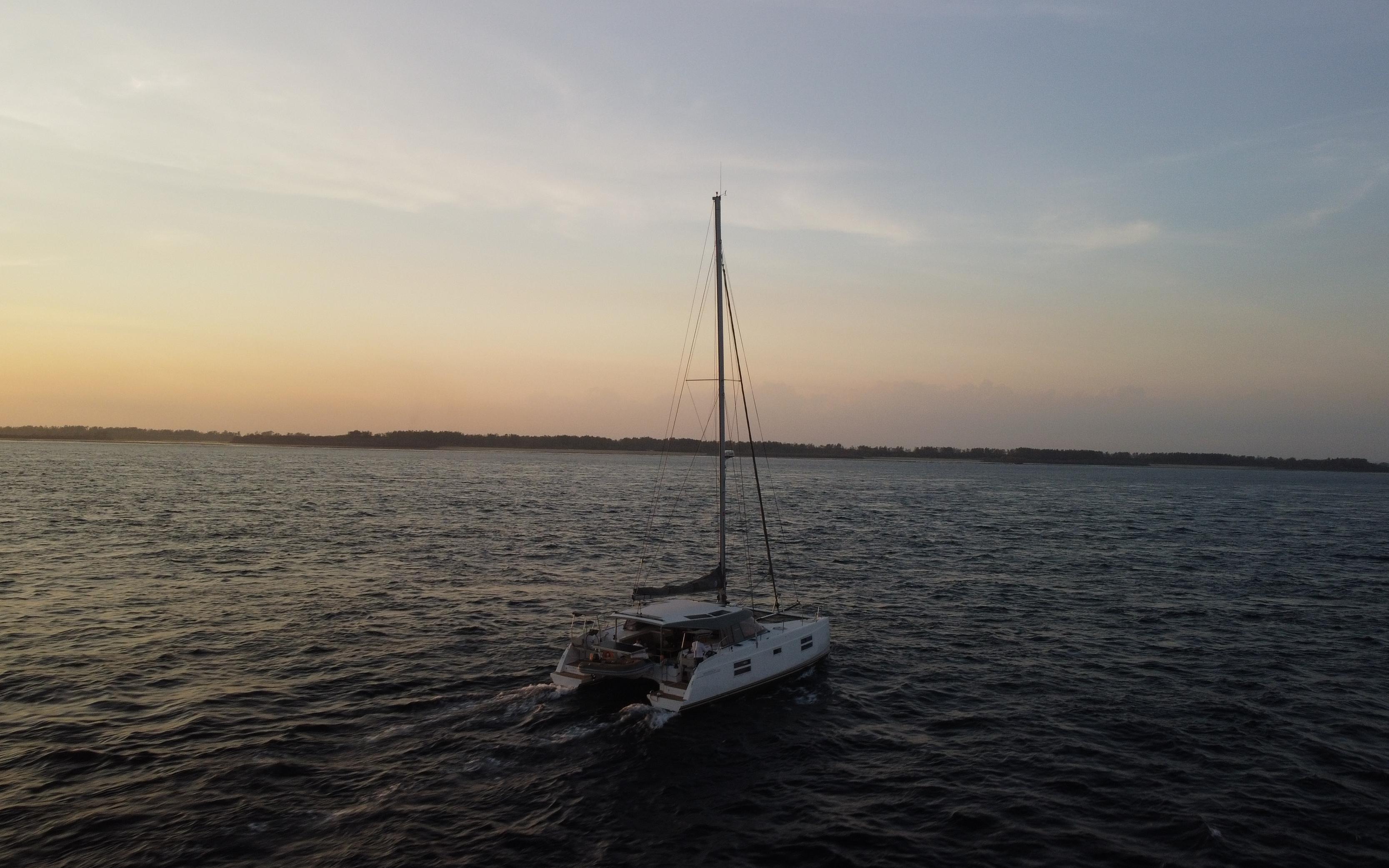 2019 Nautitech 40 Open catamaran sailing at sunset on open water.