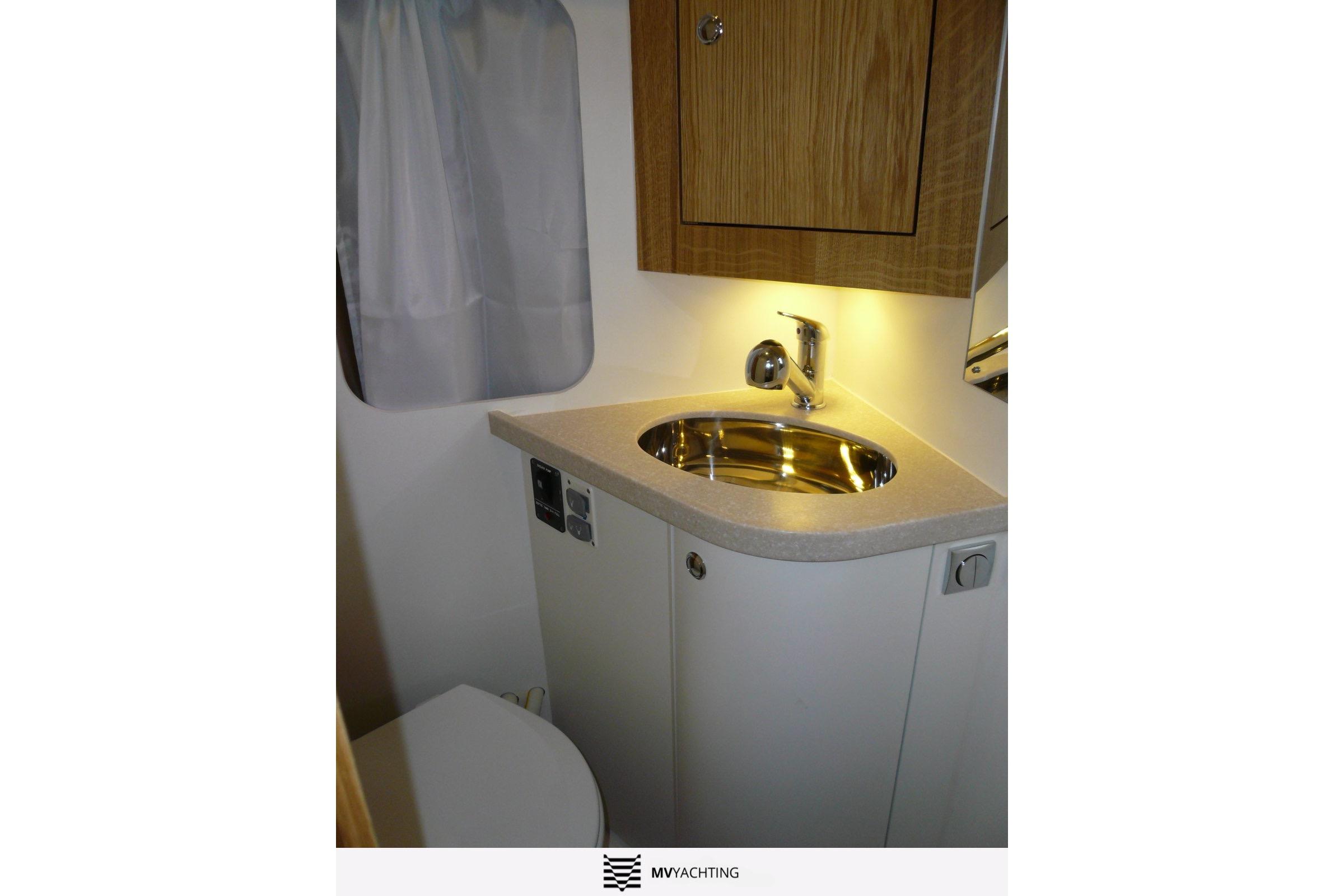 Compact bathroom in 2010 Maxi 1300 yacht with sink, faucet, and wooden cabinet.