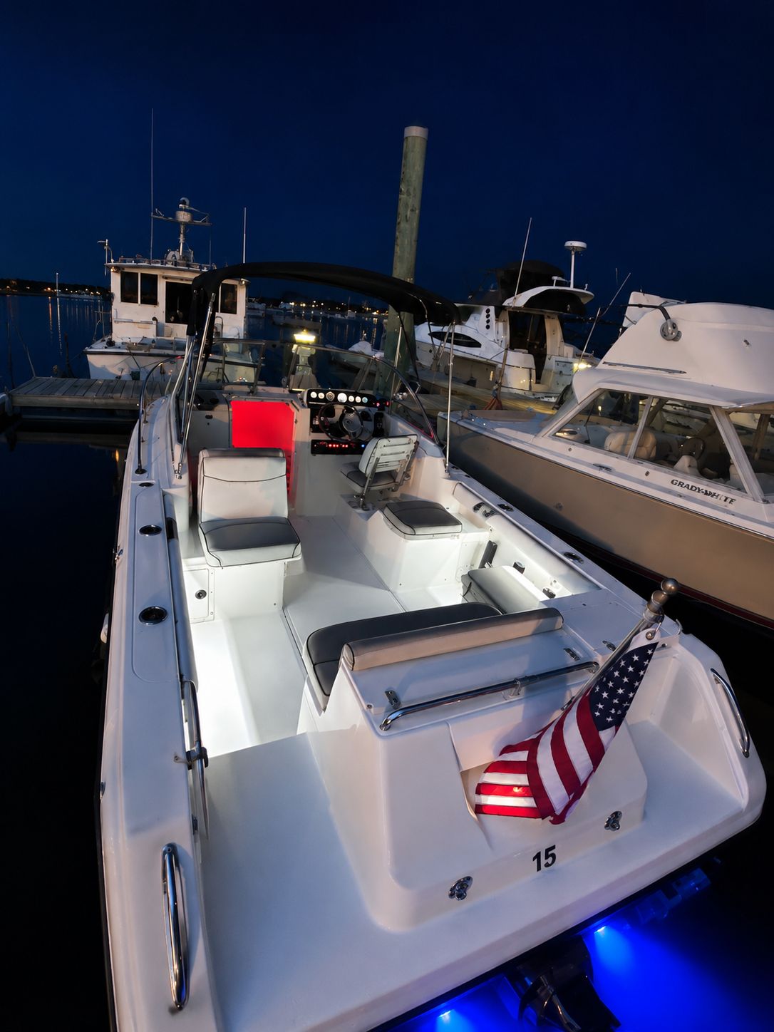 1999 Pursuit Denali boat docked at night, illuminated with lights.