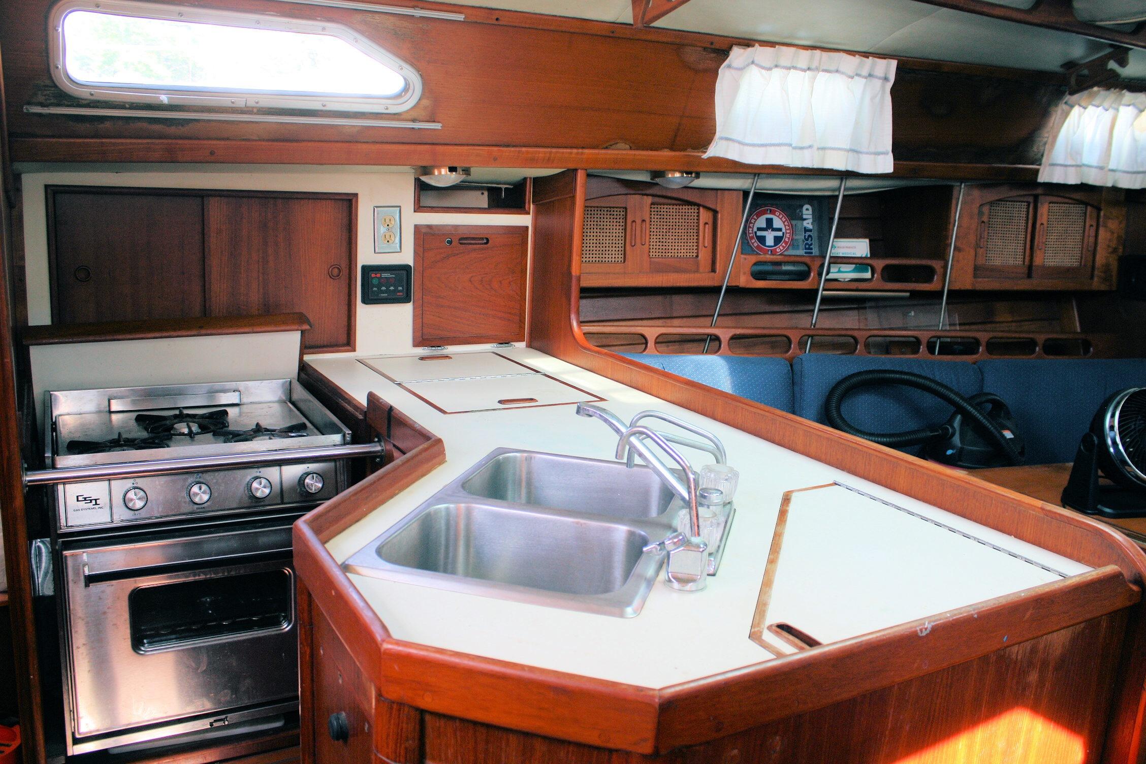 Interior of 1987 Ericson 38-200 sailboat galley with stove, sink, and wooden cabinetry.