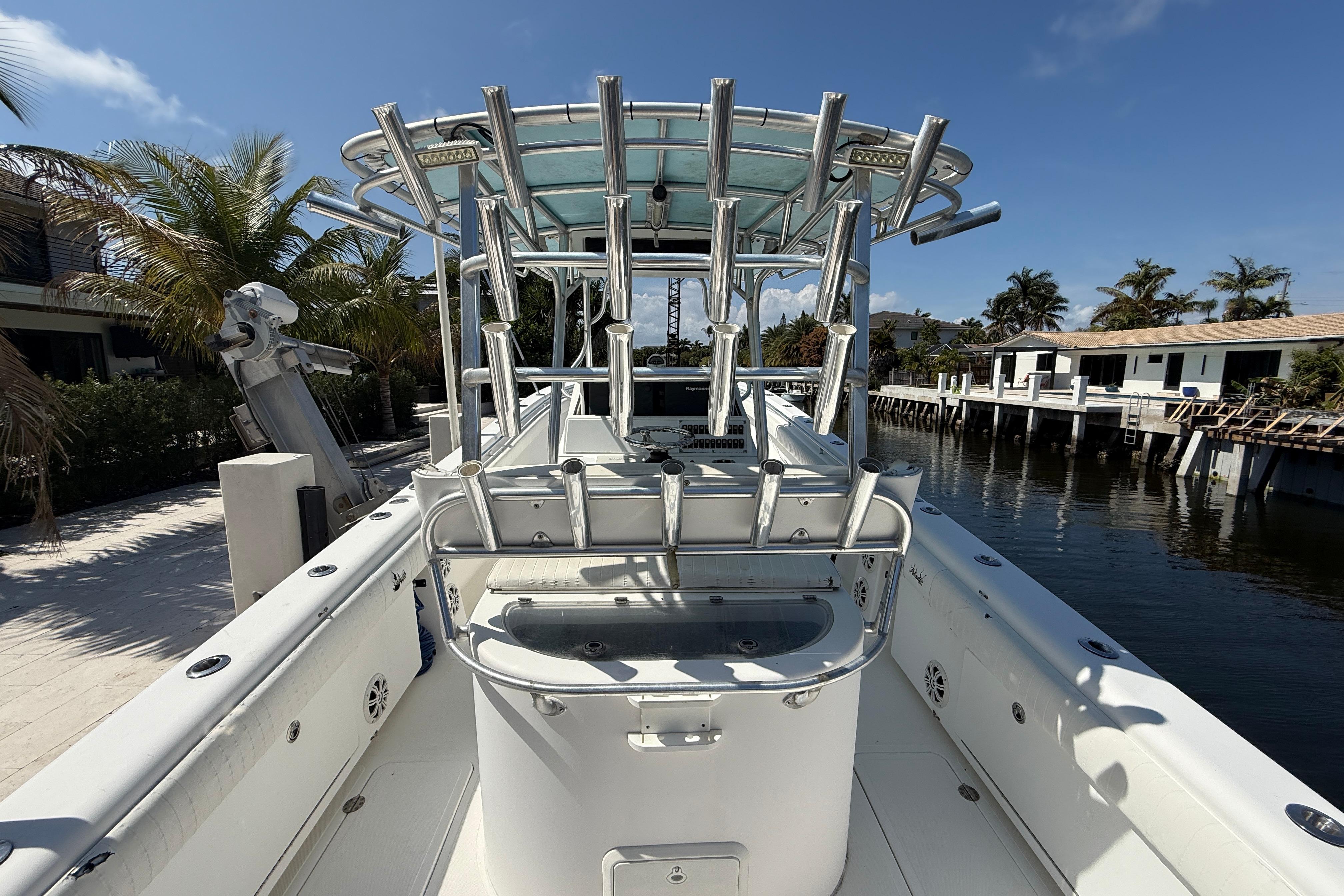 2003 Palmetto 33 Adventure boat docked by waterfront homes, featuring a spacious deck and rod holders.