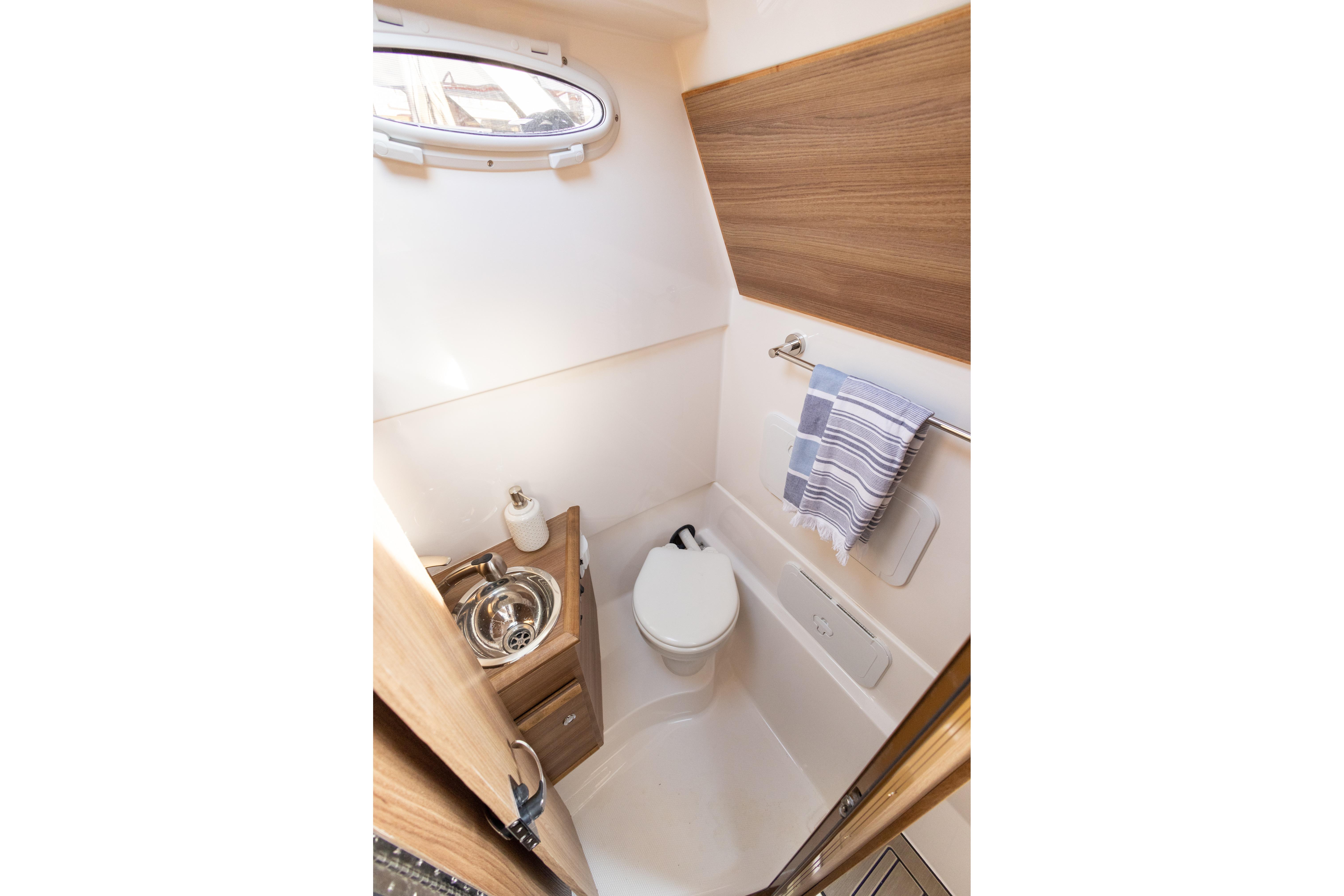 Compact bathroom in 2025 Solara S-310 CW boat with sink, toilet, and towel rack.
