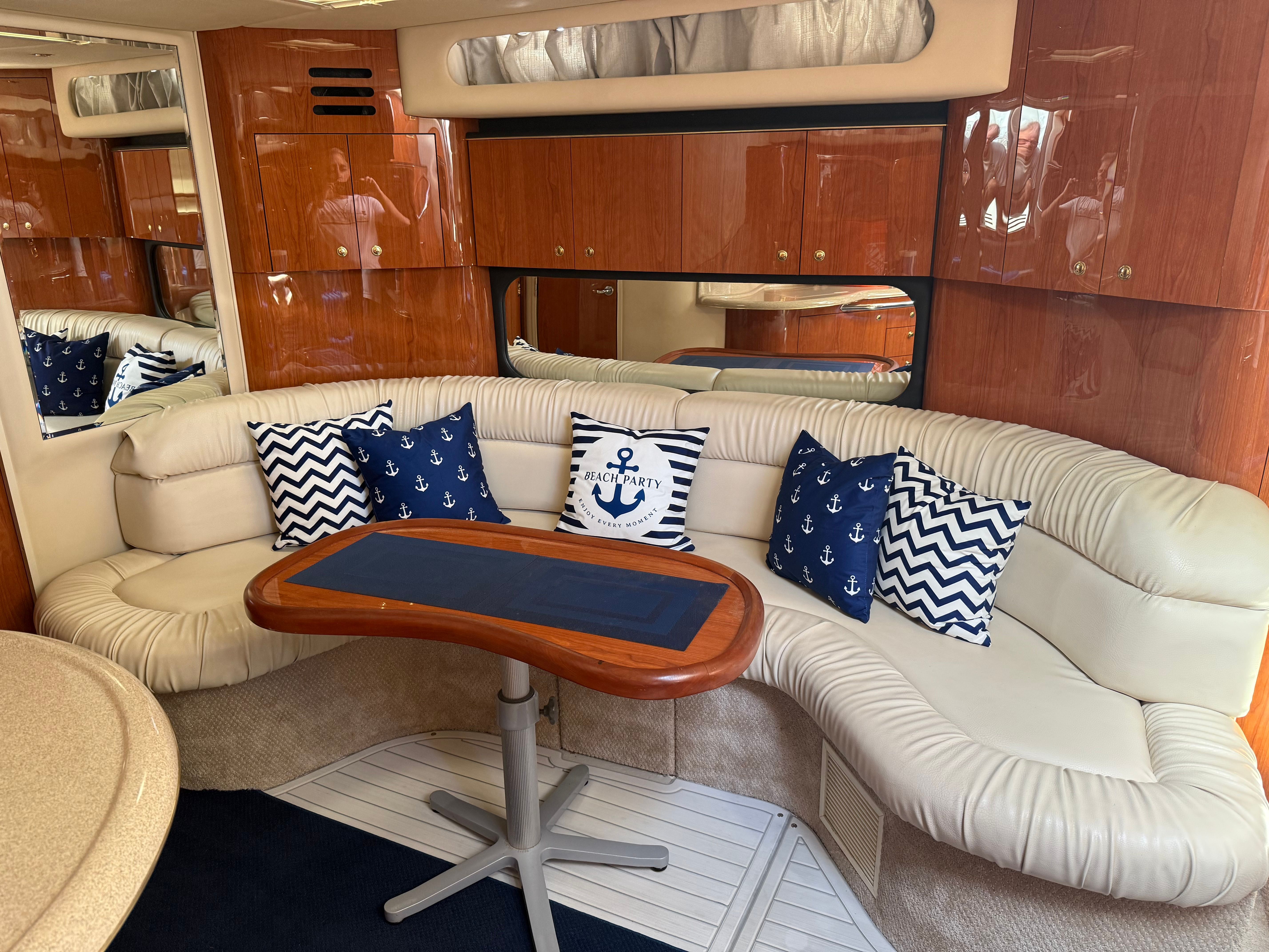 Interior of a yacht with white leather sofa and nautical-themed pillows.