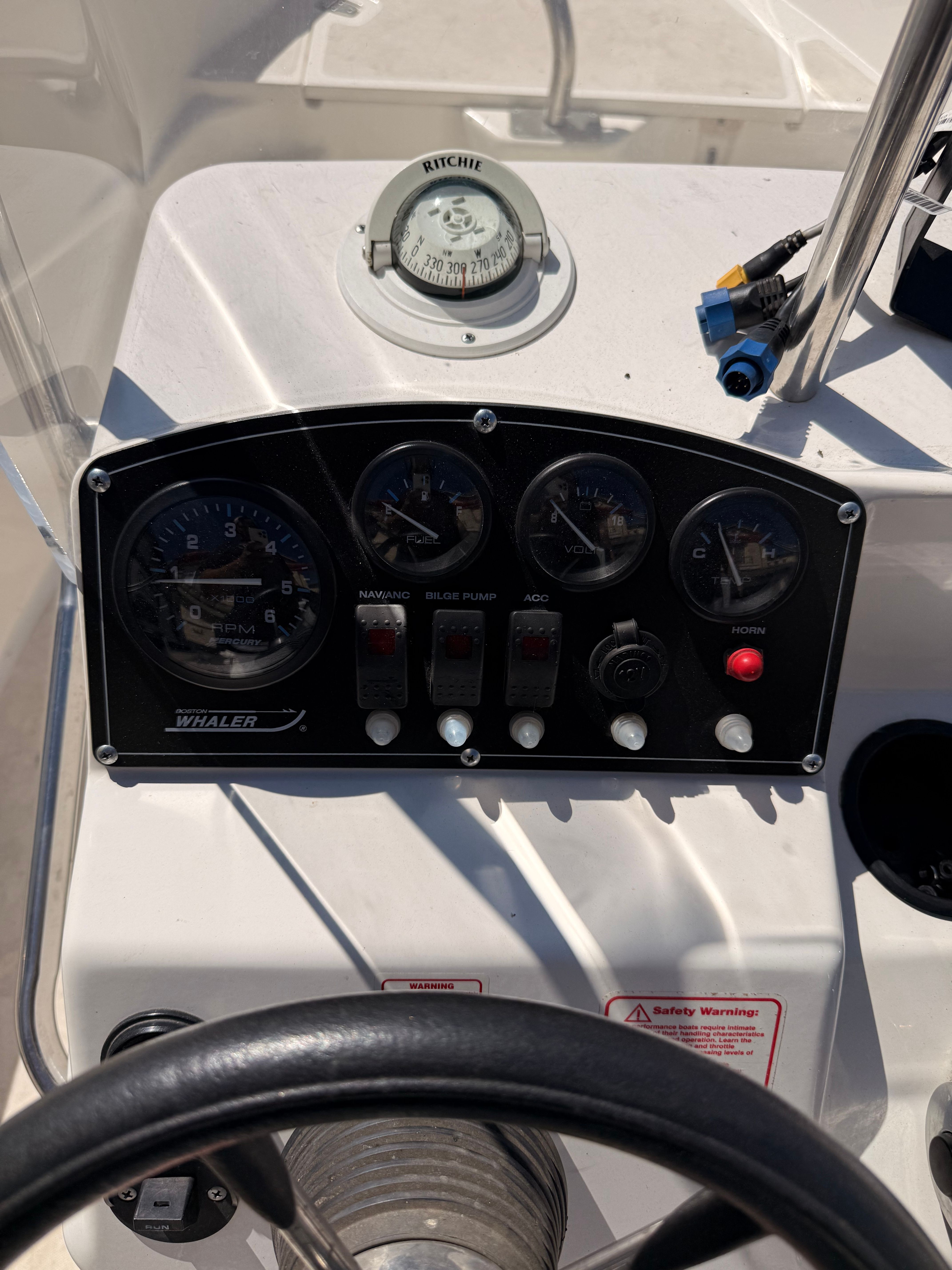 Dashboard of a Boston Whaler 160 Dauntless with various gauges and a compass.