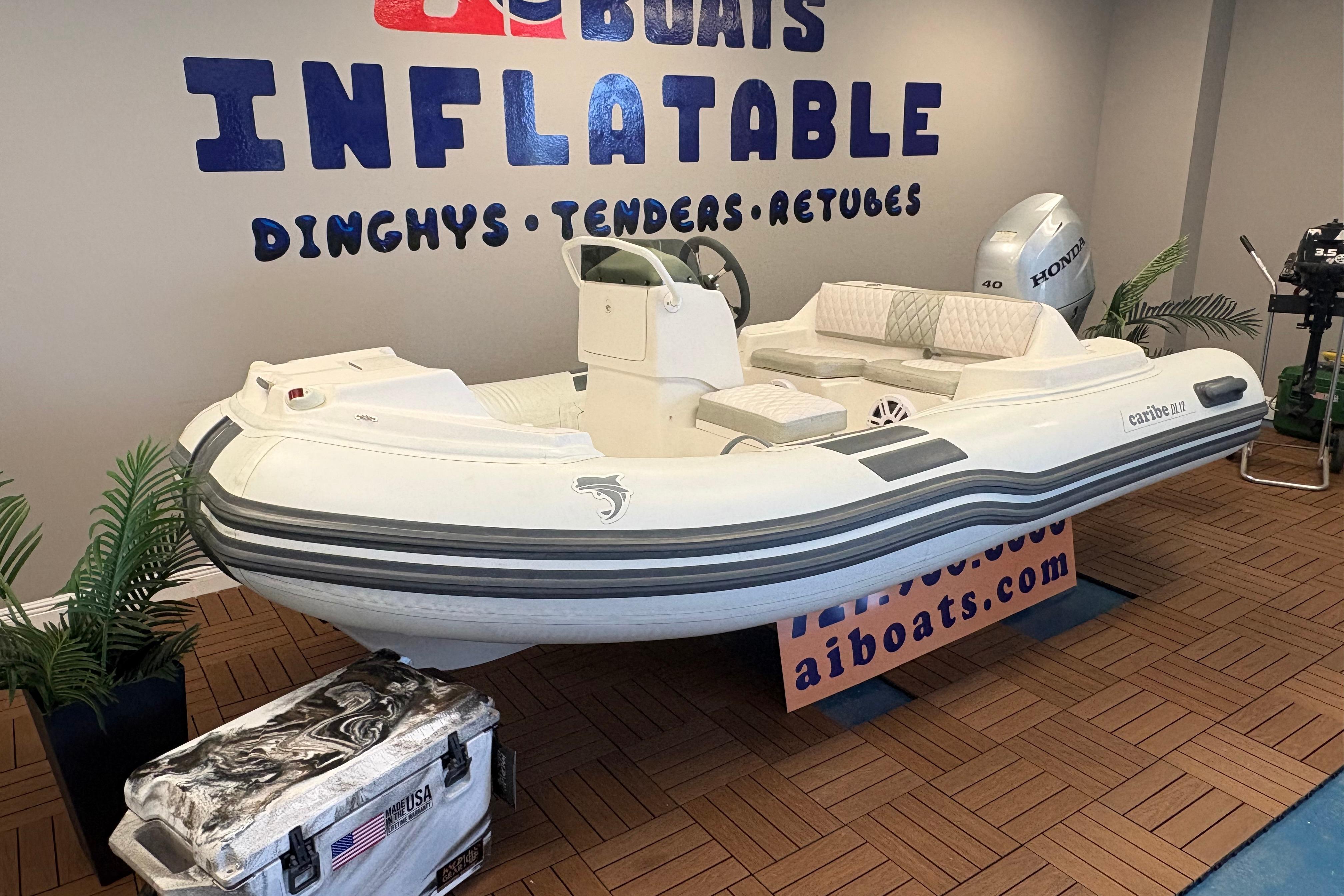 2019 Caribe DL12 inflatable boat displayed indoors with Honda engine and promotional signage.