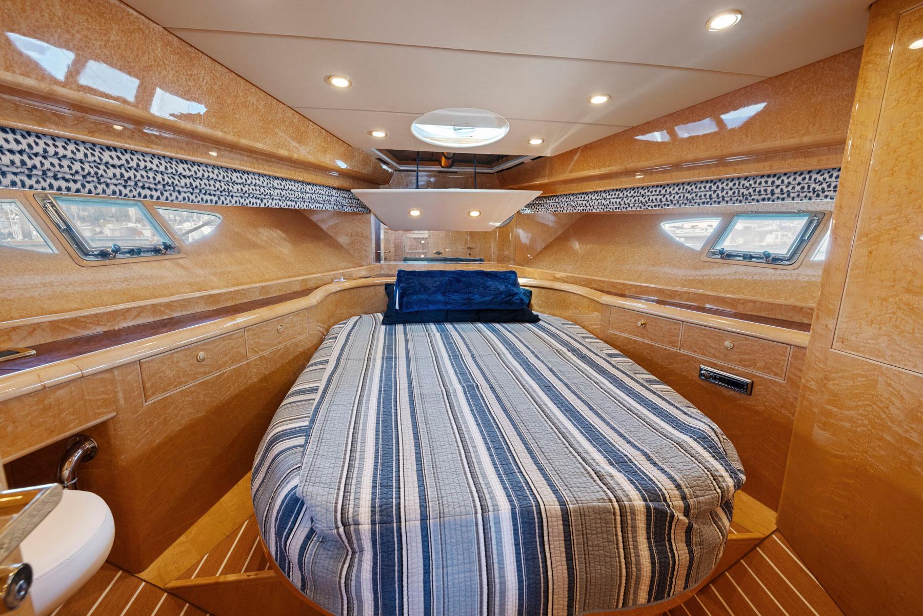Luxurious 2008 Dyna 51 yacht cabin with striped bedding and elegant wood finish.