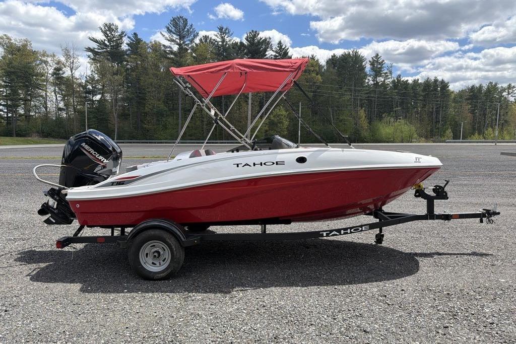 2026 Tahoe T16 boat with red hull and canopy on a trailer, parked outdoors.